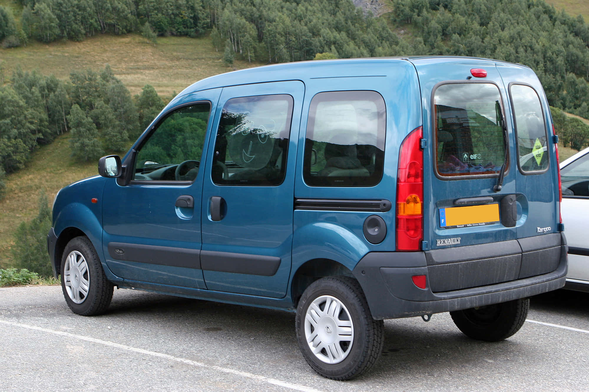 Renault Kangoo 桌布 壁紙 — 一輛藍色雷諾Kangoo客貨車停泊在停車場，背景是綠色的森林山丘。