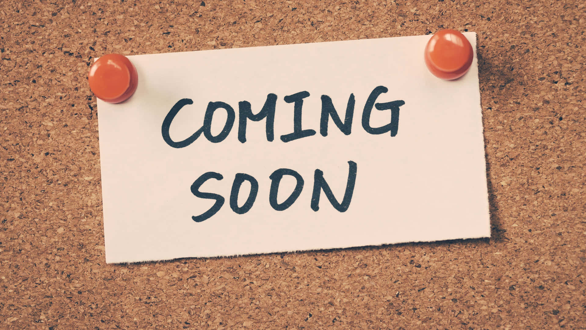 一張用大頭針釘在軟木板上的便條寫著coming soon。