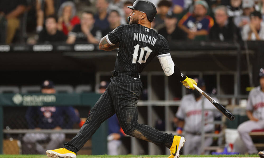 Yoan Moncada 擊球後的瞬間 壁紙 — 棒球手Moncada身穿黑色細條紋球衣，在夜間比賽中揮棒，背景有觀眾。