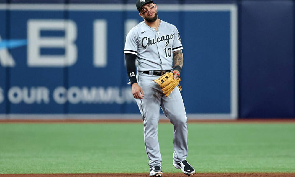 Yoan Moncada 站在棒球場上 壁紙 — 一位芝加哥棒球手身穿灰色球衣，在綠色球場上戴著手套，站在體育場燈光下。