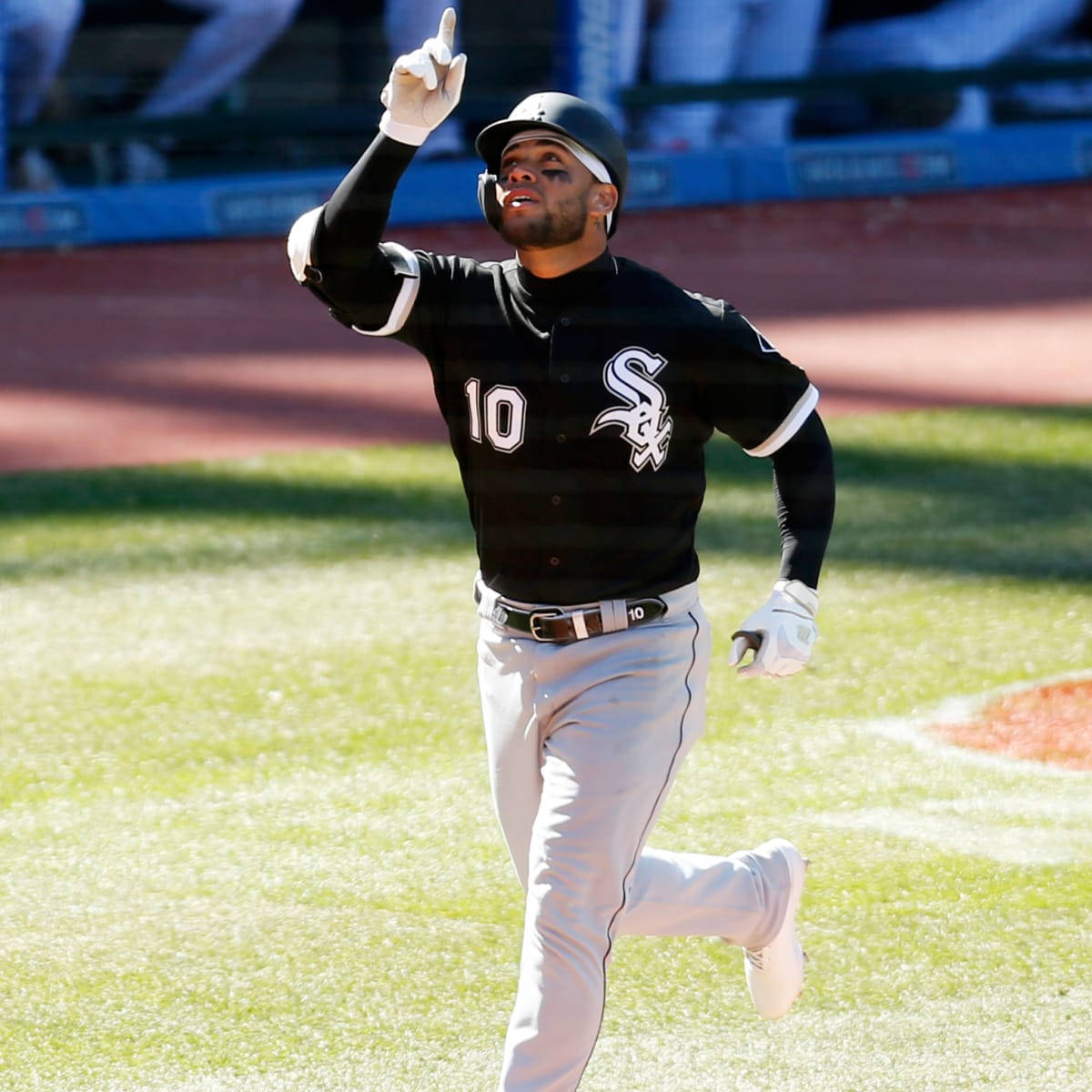 Yoan Moncada 跑動並指向上方 壁紙 — 一名芝加哥白襪棒球選手身穿黑色球衣，在陽光明媚的球場上奔跑，向上指著慶祝。
