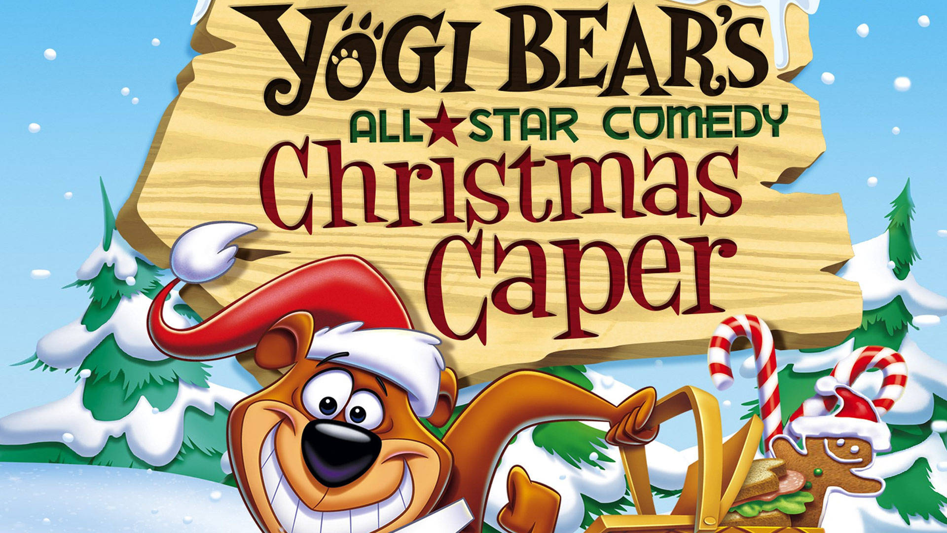 Yogi Bear 圣誕大冒險 壁紙 — 戴著聖誕帽的瑜伽熊在雪白的冬日場景中，與拐杖糖和薑餅人一起開心地咧嘴笑。