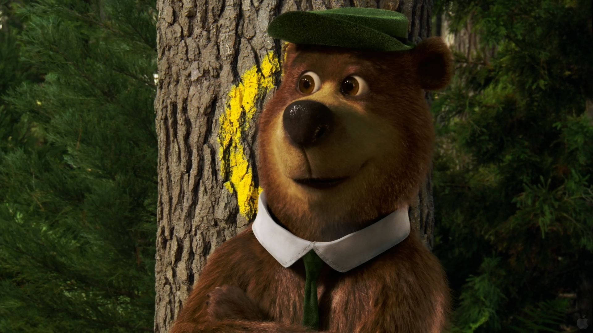 Yogi Bear 對準靶心 壁紙 — 一隻迷人的3D渲染熊，戴著綠色帽子和領帶，靠在一棵茂密森林中長滿苔蘚的樹幹上。