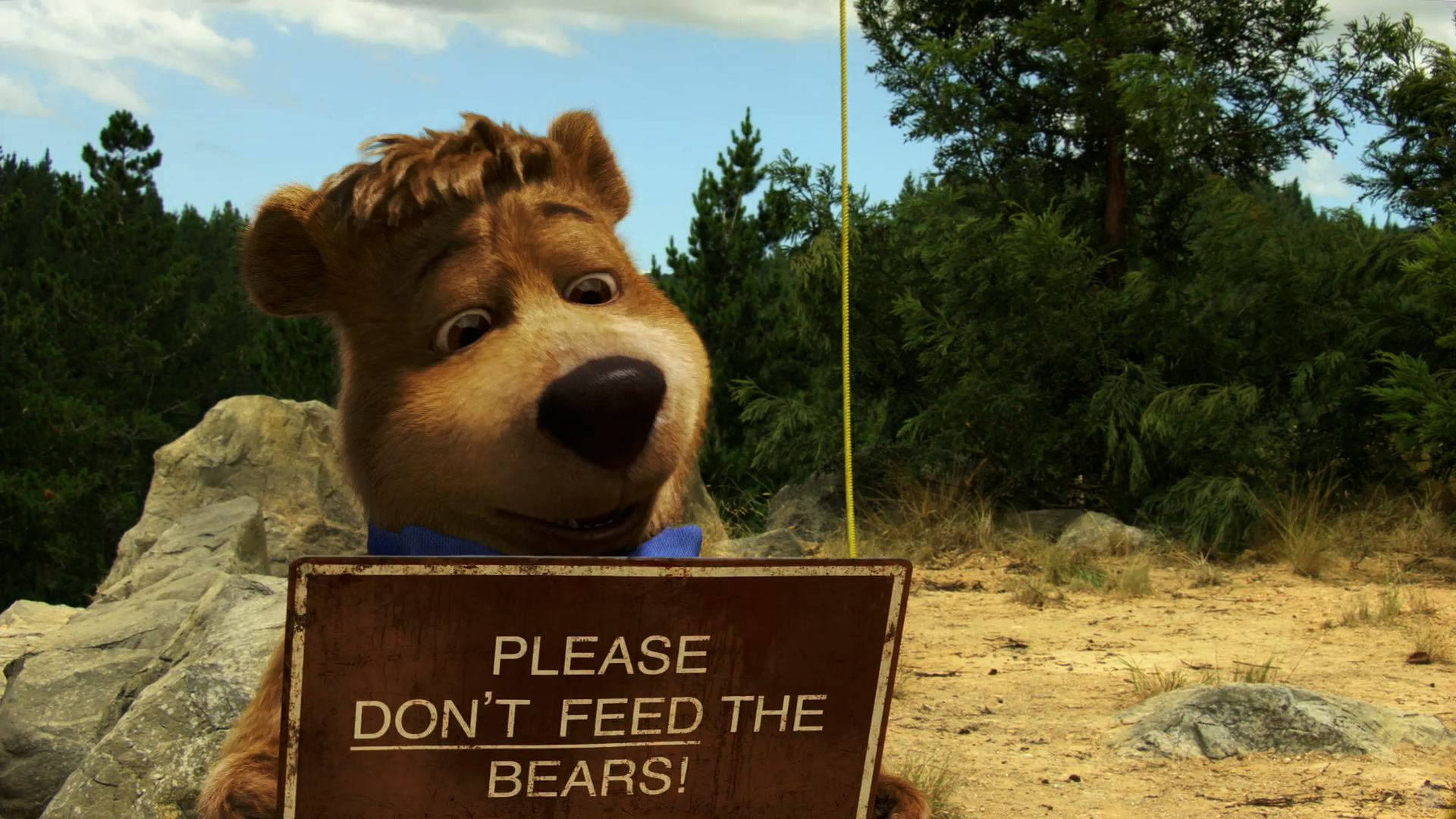 Yogi Bear與Boo Bear的標語 壁紙 — 一隻友善的動畫熊在森林空地中拿著一個生鏽的牌子，懇求不要餵熊。