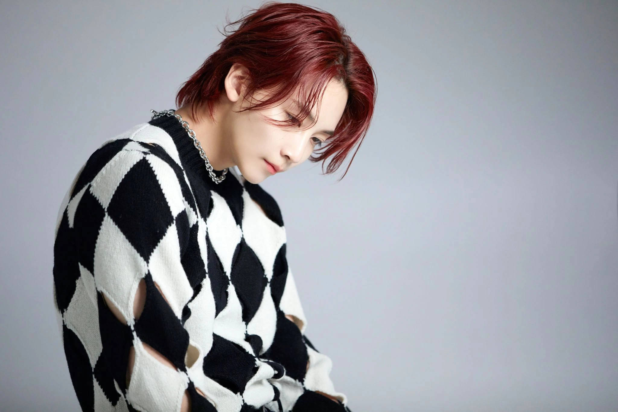 Yoon Jeonghan 為 Cosmopolitan 專訪 壁紙 — 一個紅髮的人穿著黑白菱形圖案毛衣，背景是純灰色。