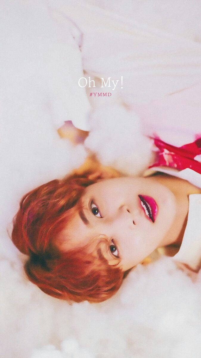 Yoon Jeonghan Oh My! 壁紙 — 一位紅髮、嘴唇大膽粉紅的年輕人躺在柔軟的白雲上，帶著俏皮的表情向上看。