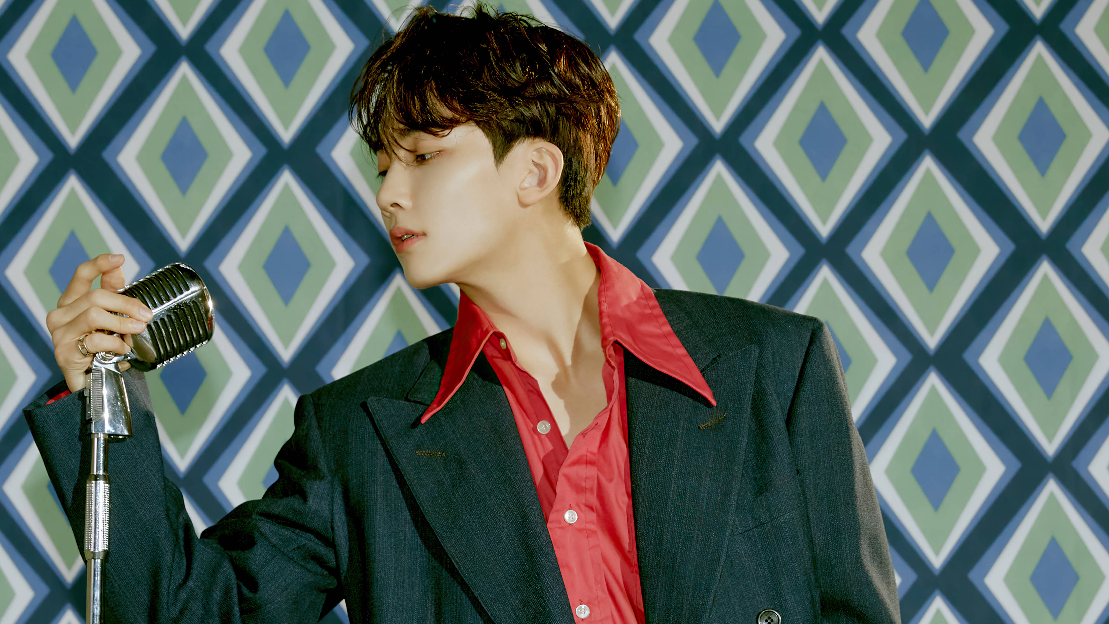 Yoon Jeonghan 复古概念 壁紙 — 一位身穿紅襯衫和深色西裝的年輕男子，手持復古麥克風，背景是鮮明的幾何圖案牆壁。