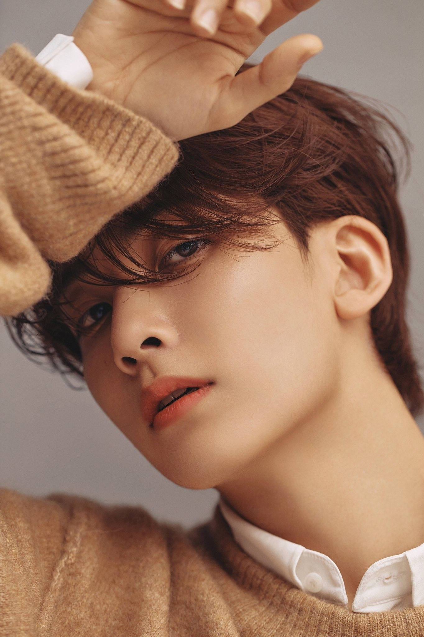 Yoon Jeonghan 為 Bazaar V China 專訪 壁紙 — 一位棕色頭髮、藍色眼睛的年輕男子，身穿米色毛衣，手放在頭上，向上凝視。