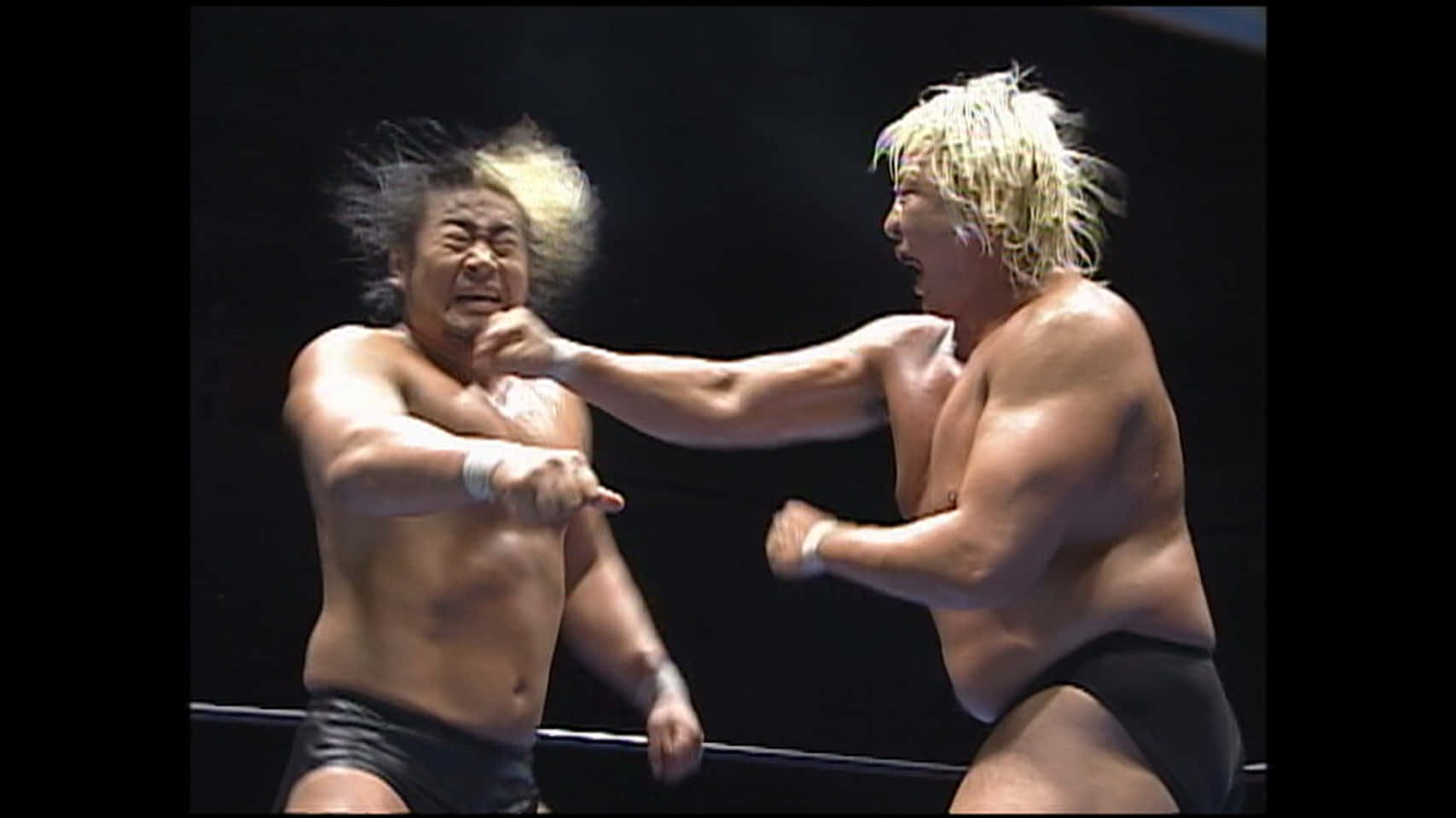 Yoshihiro Takayama 與 Sumawa 壁紙 — 兩位肌肉發達的摔角手在擂台上碰撞，一位金髮一位黑髮，兩人在明亮的場館燈光下正揮出拳頭。
