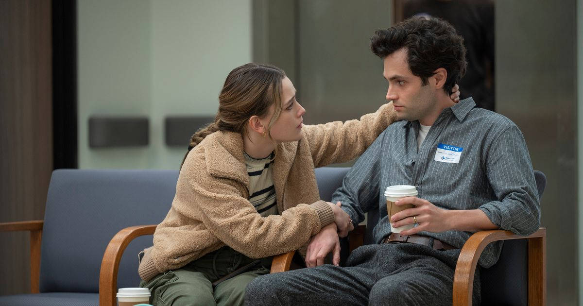 《You》劇中Love Quinn與Joe Goldberg 壁紙 — 一位身穿米色外套的女性輕輕觸碰一位男士的肩膀，他們緊靠著坐在現代化等候室的藍色椅子上。