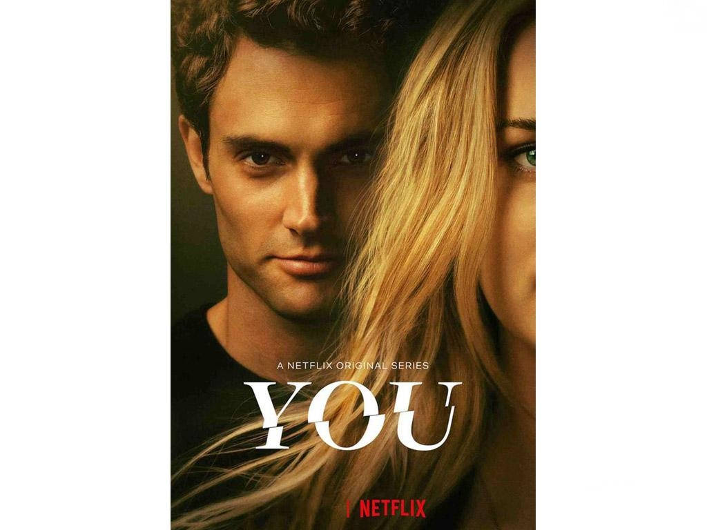 《You》劇集主角 Joe Goldberg 海報 壁紙 — 一男一女近距離接觸，在溫暖燈光下眼神交織，帶有標題「YOU」和Netflix品牌標誌。