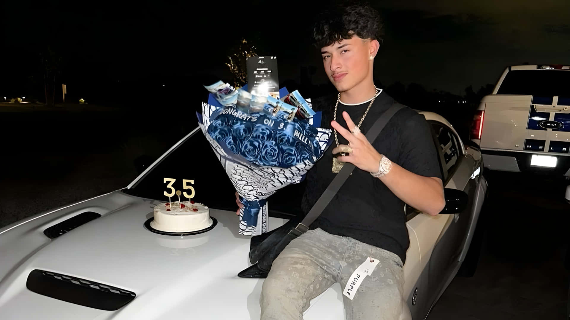  壁紙 — 一名年輕男子晚上坐在白色跑車上，手持一束藍玫瑰和一個插有3.5支蠟燭的蛋糕。