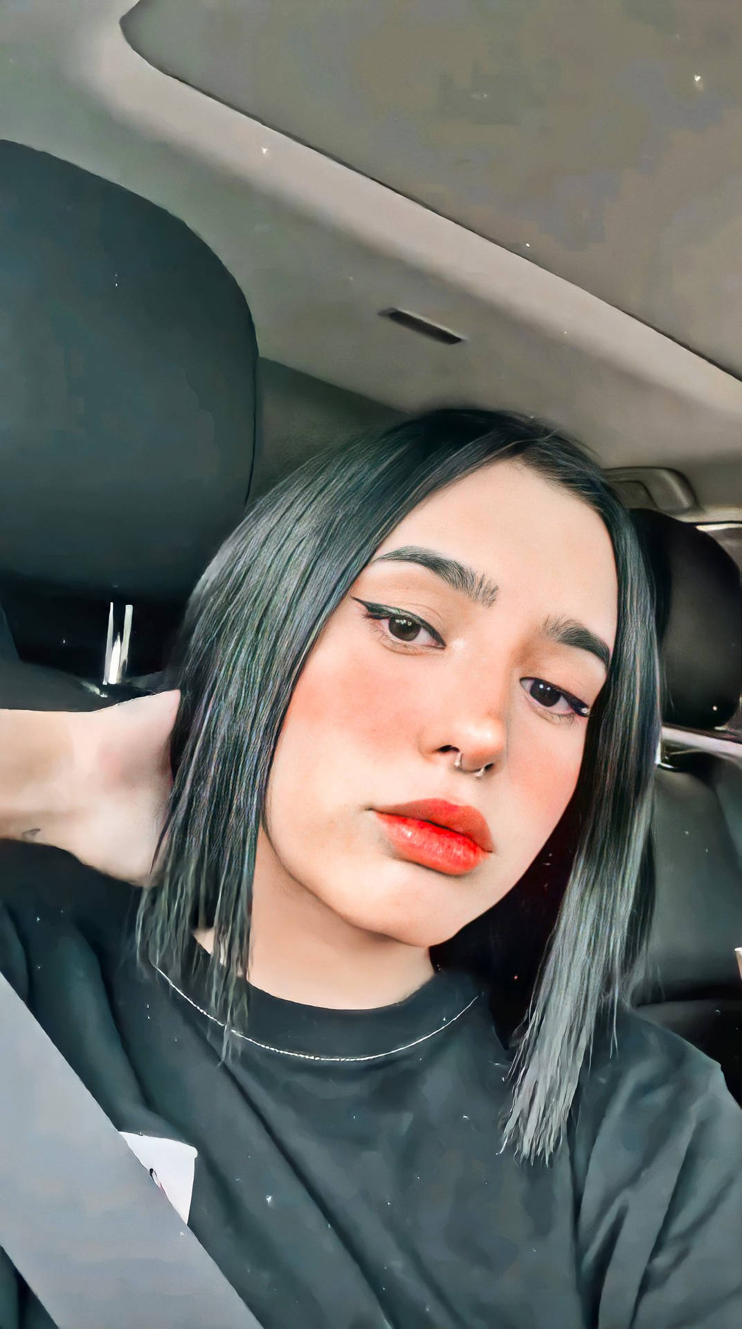 黑髮紅唇的年輕女性坐在車內，身穿黑色襯衫。