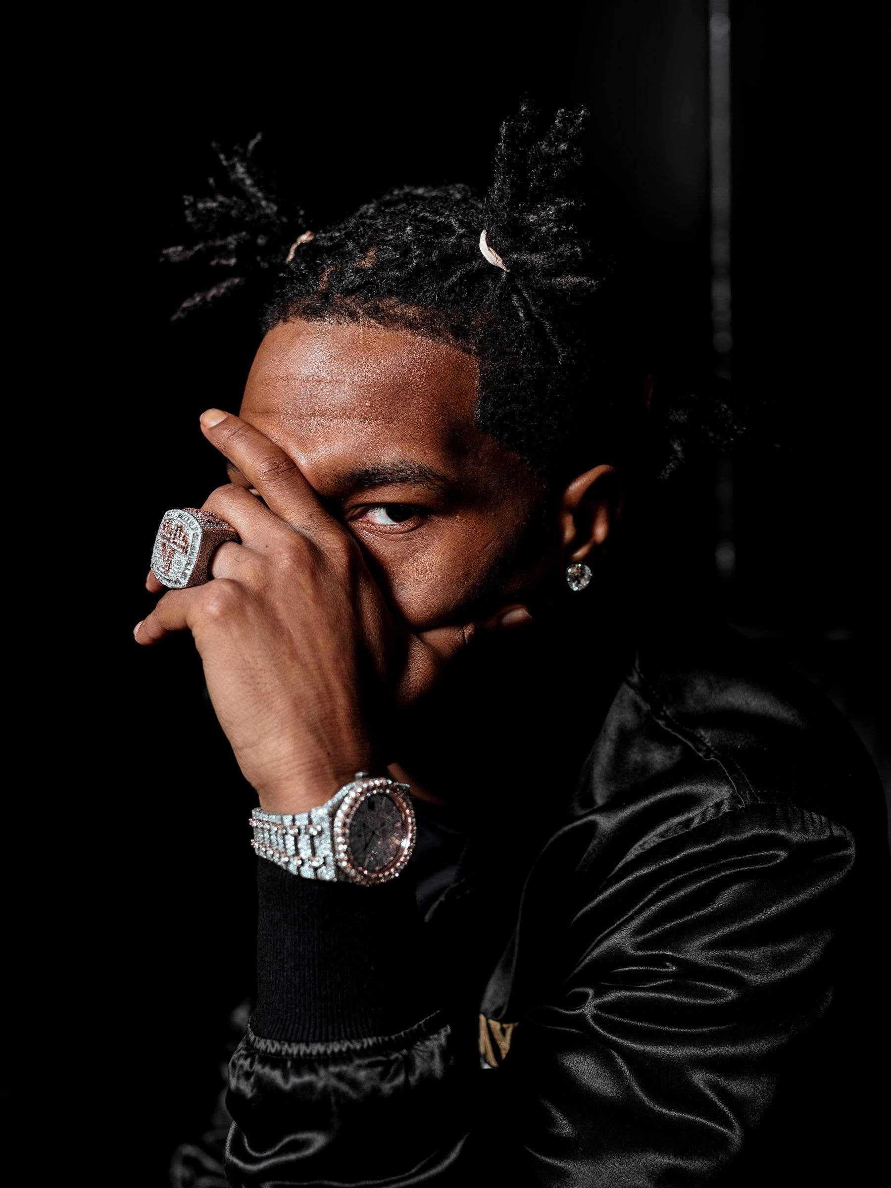 Youngboy Never Broke Again 覆面照 壁紙 — 一個留著辮子、戴著鑲鑽珠寶的男人，在純黑背景下部分遮住臉。