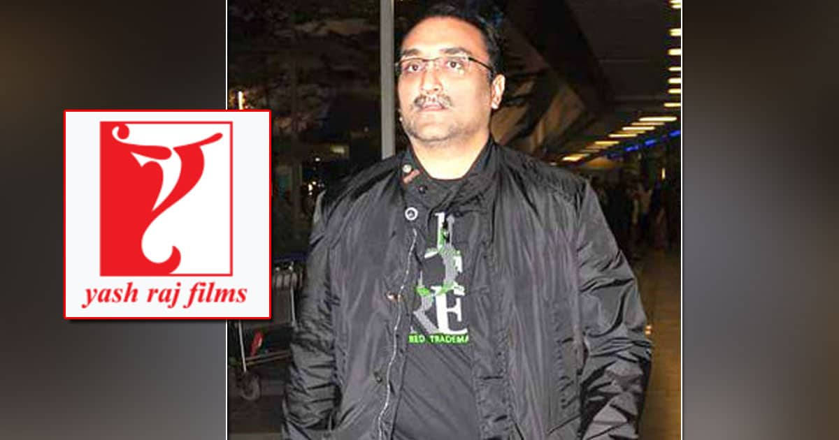 戴眼鏡和黑色外套的男子站在Yash Raj Films標誌旁邊。