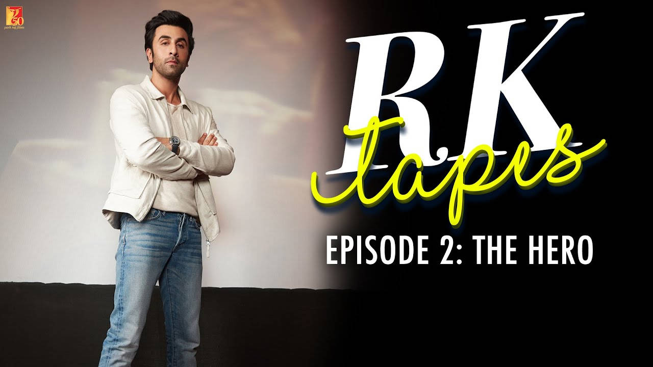 Ranbir Kapoor 身穿白色外套和牛仔褲，交叉雙臂站在「RK Tapes」文字旁。