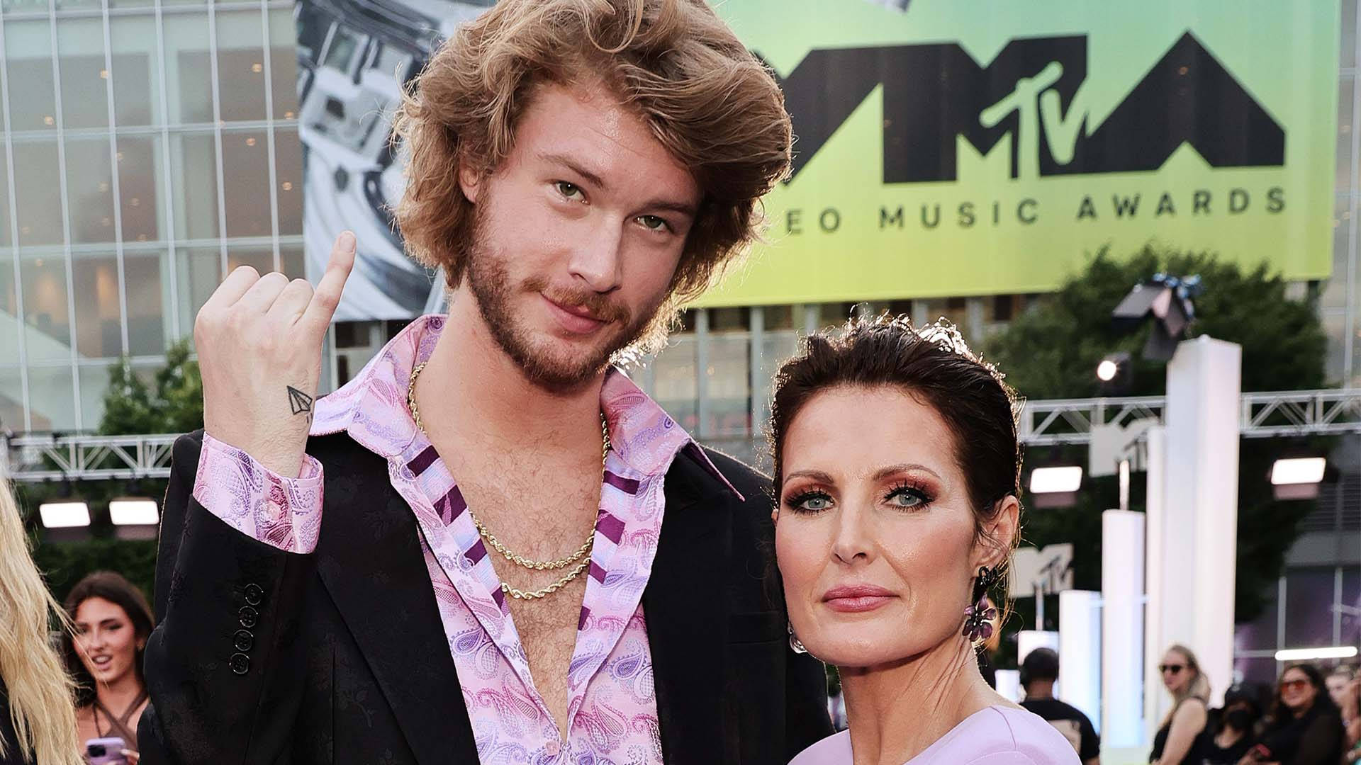 Yung Gravy 與前女友 壁紙 — 一個捲髮男人和一個女人在MTV Video Music Awards的紅地毯上自信地擺姿勢，背景有明亮的燈光和綠色背景。