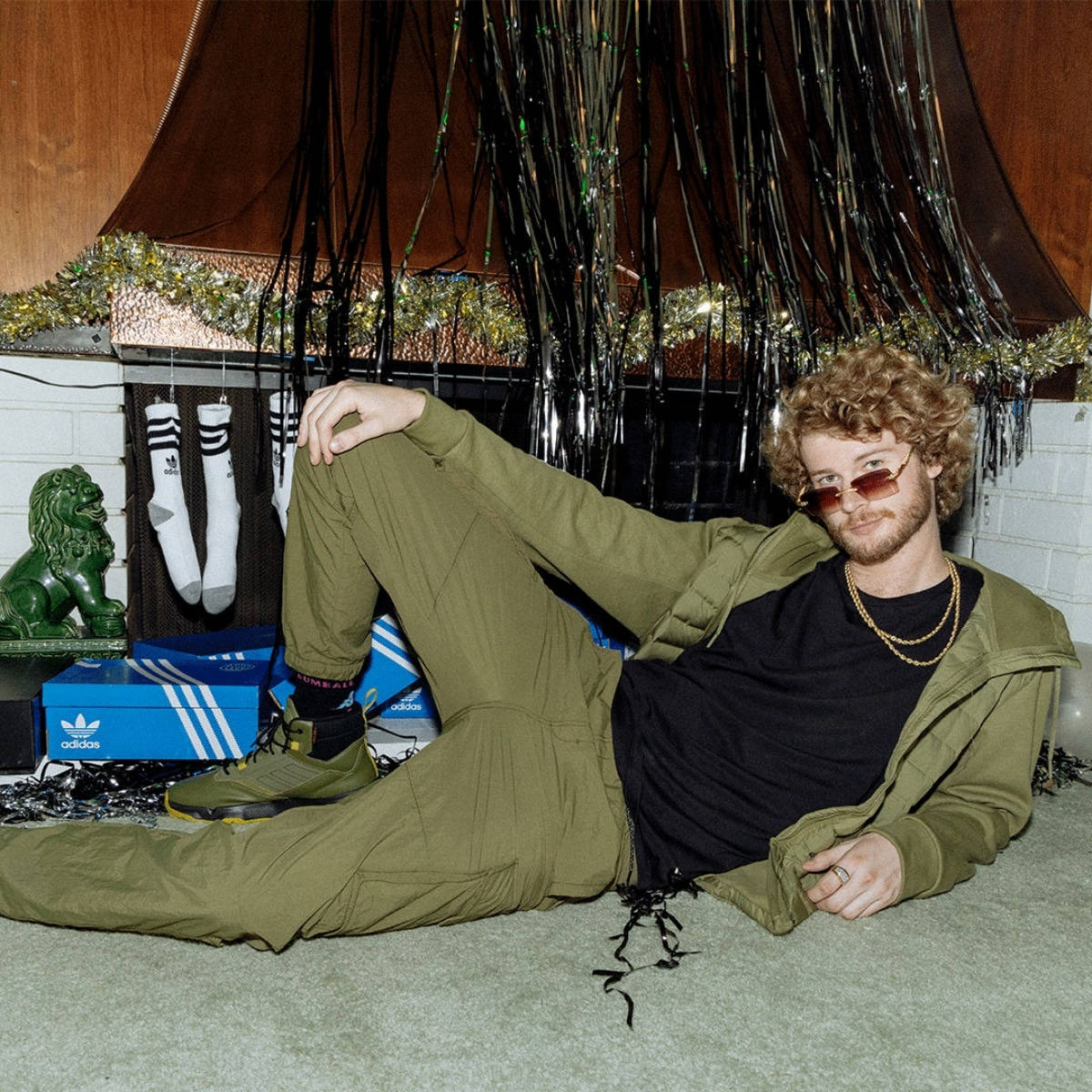穿綠色衣服的男人與Adidas盒子和裝飾一起休息。
