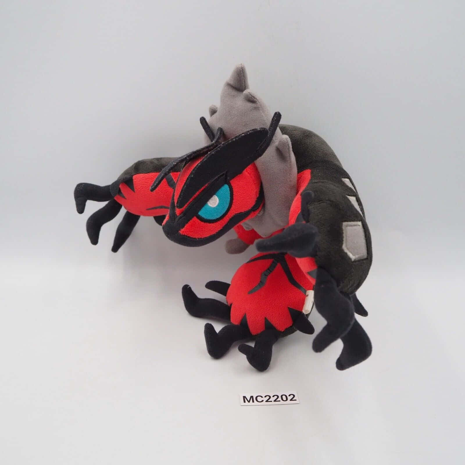 Yveltal 毛絨玩具側面視圖 壁紙 — 一隻擁有紅色、黑色和灰色毛髮以及明亮藍色眼睛的寶可夢索羅亞克毛絨玩具，擺放在純白色背景前。