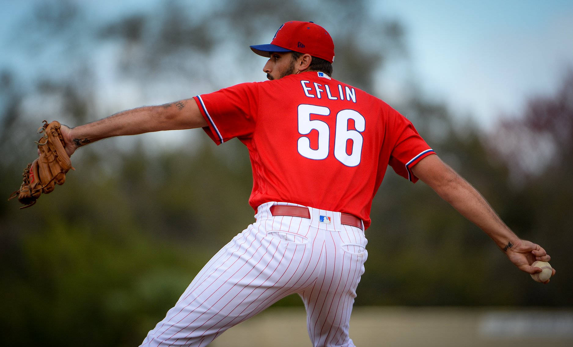 Zach Eflin 即將投球 壁紙 — 一位身穿紅色球衣、背號56的棒球投手，正準備在模糊的戶外背景下投球。