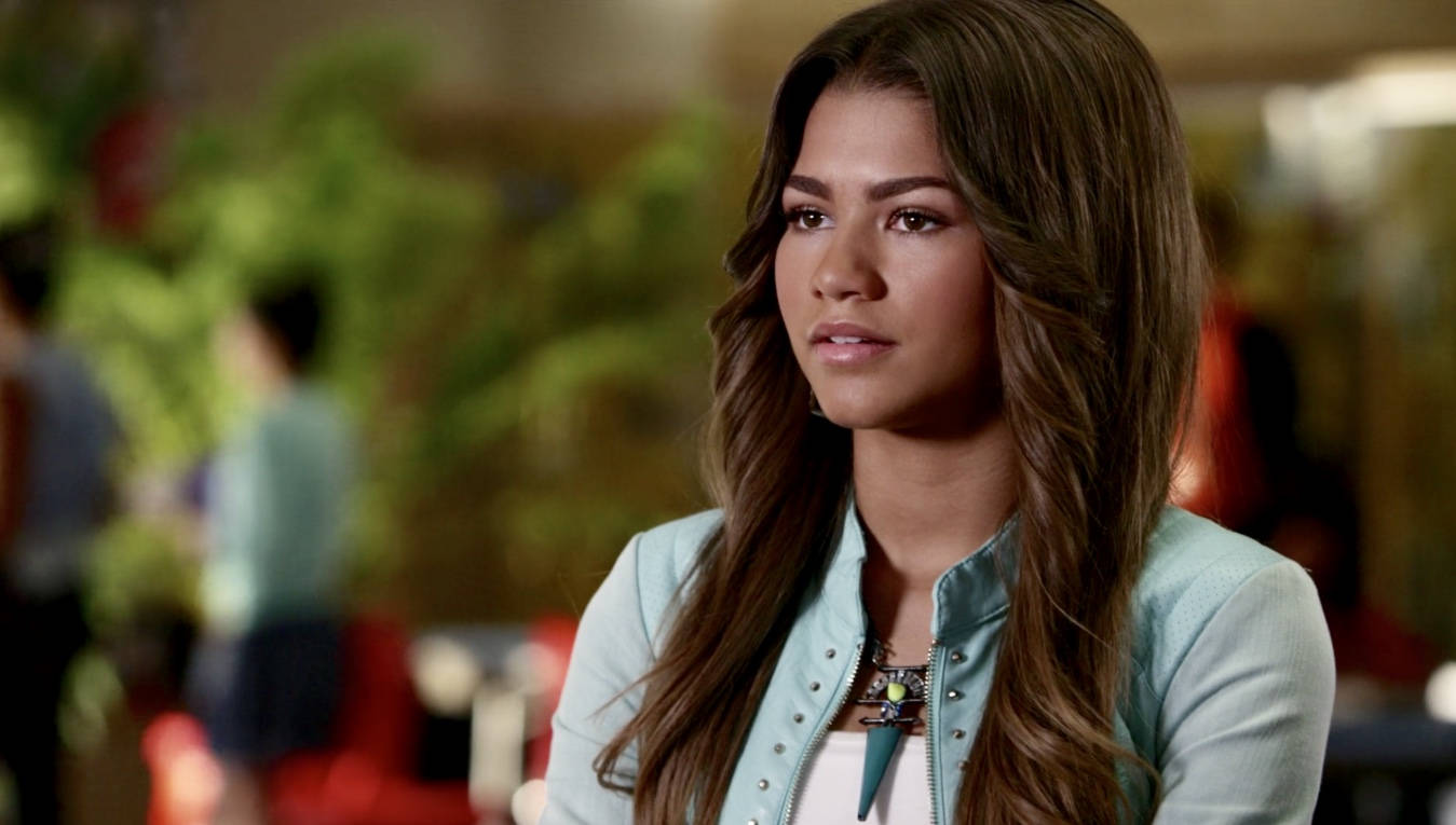 Zendaya 身穿輕便外套，在室內若有所思，背景模糊。