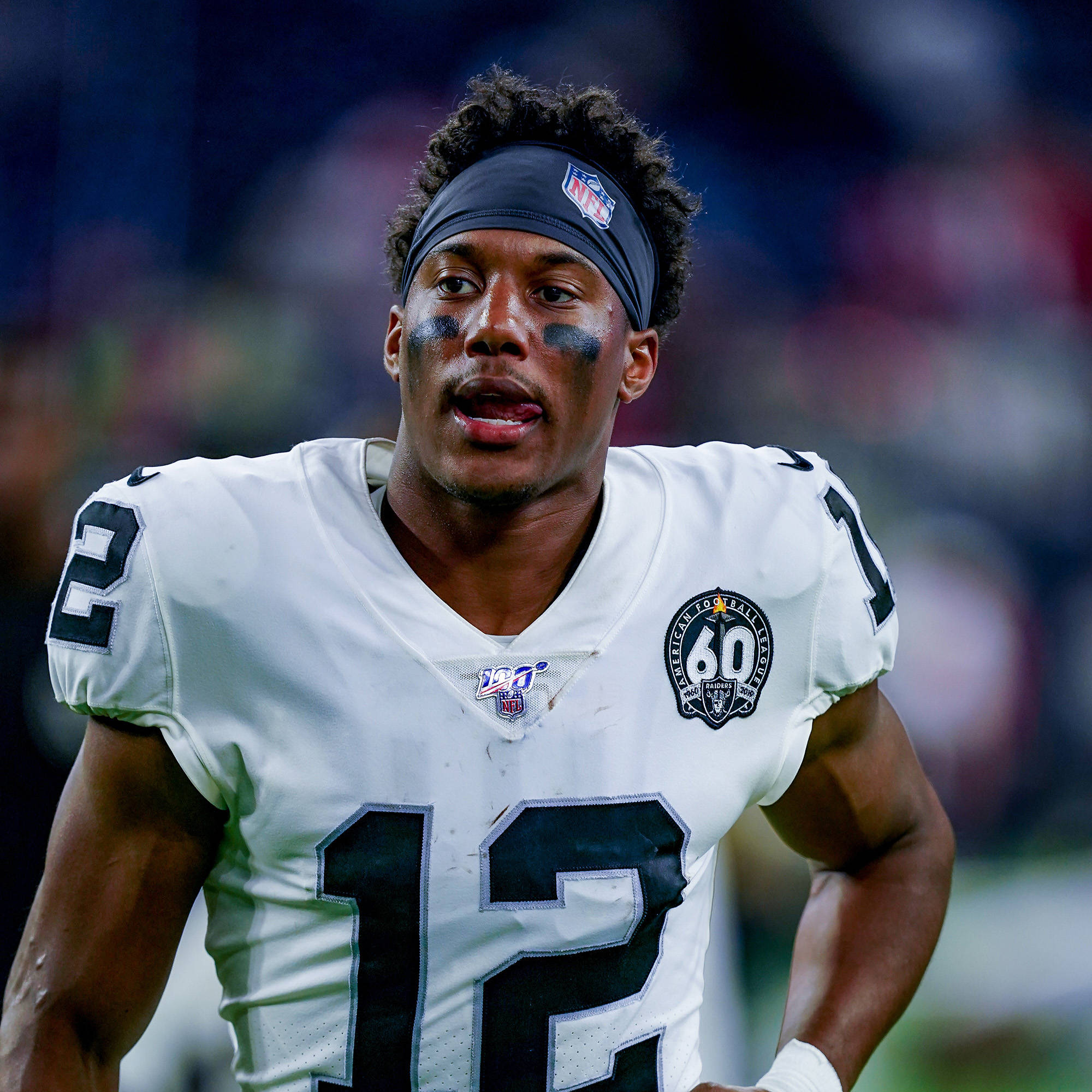 Zay Jones 半身照 壁紙 — 一名專注的NFL美式足球員，身穿白色12號球衣，臉上塗有黑色顏料，在球場燈光下比賽中凝視前方。