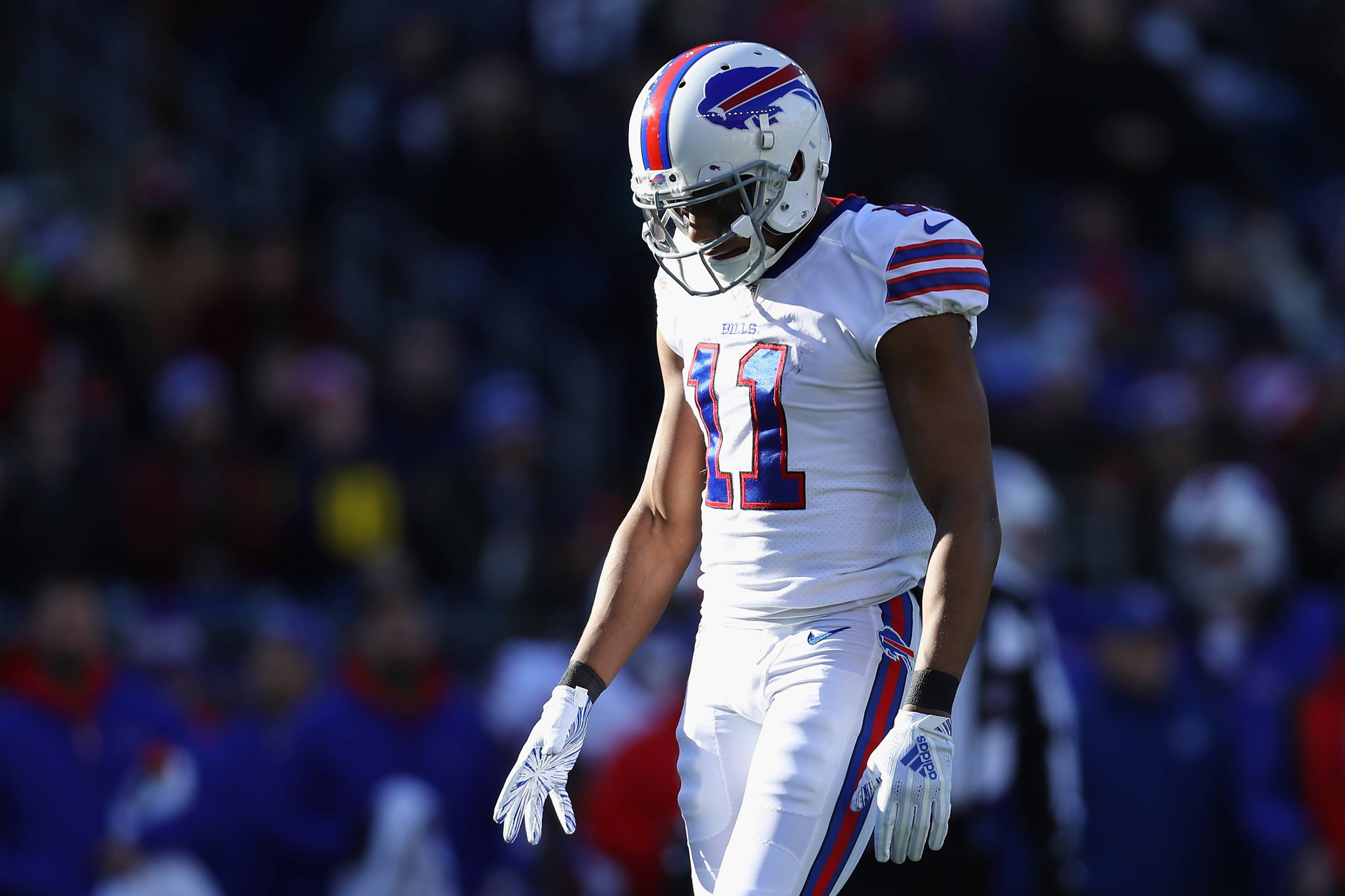 Zay Jones 水牛城比爾隊白球衣 壁紙 — 一位身穿白色球衣、背號11號的布法羅比爾隊美式足球員，在明亮的日光下走進球場，背景是模糊的人群。