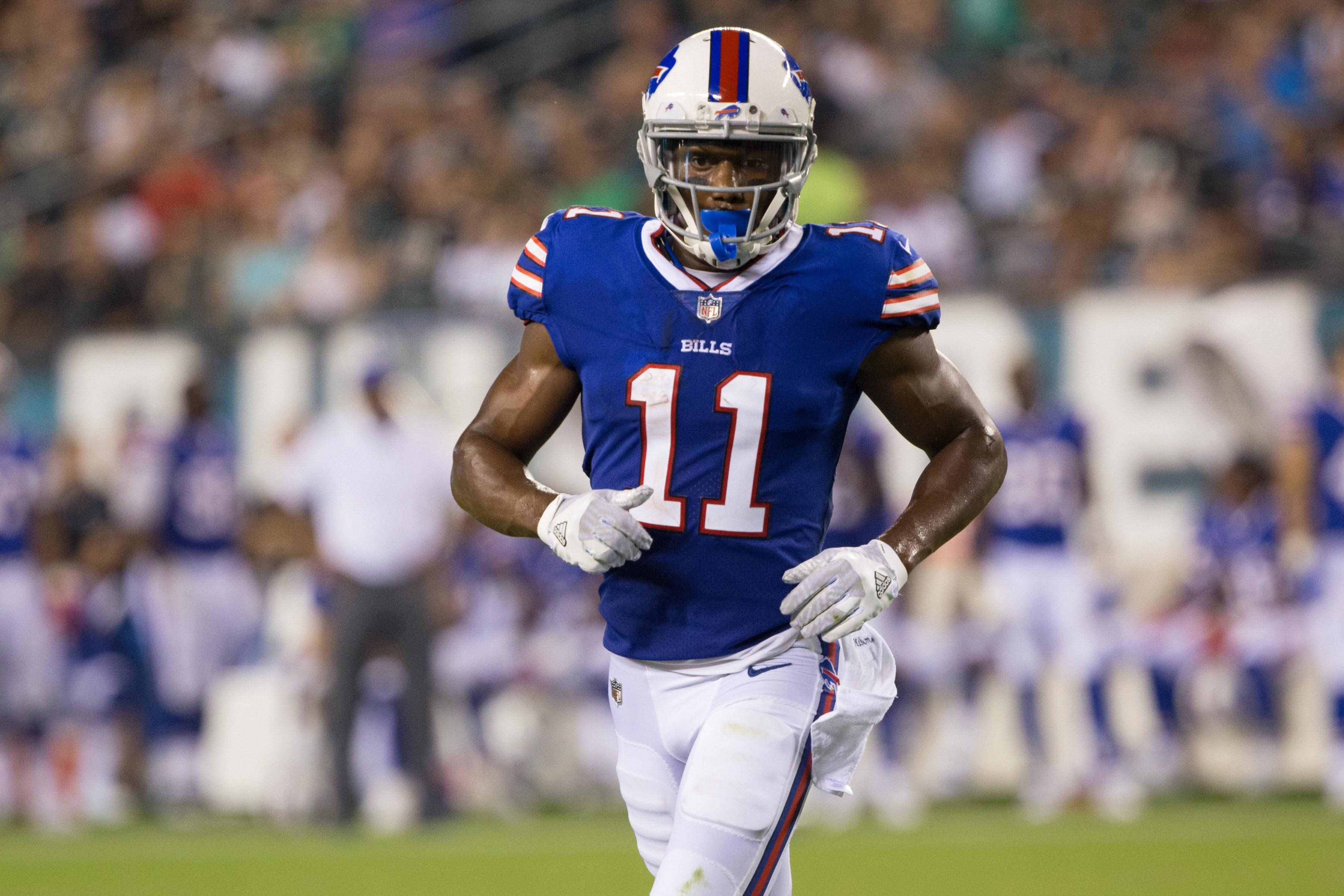 Zay Jones 足球場上 壁紙 — 一名身穿藍白球衣的水牛城比爾隊美式足球員在夜間比賽中於球場燈光下衝刺。