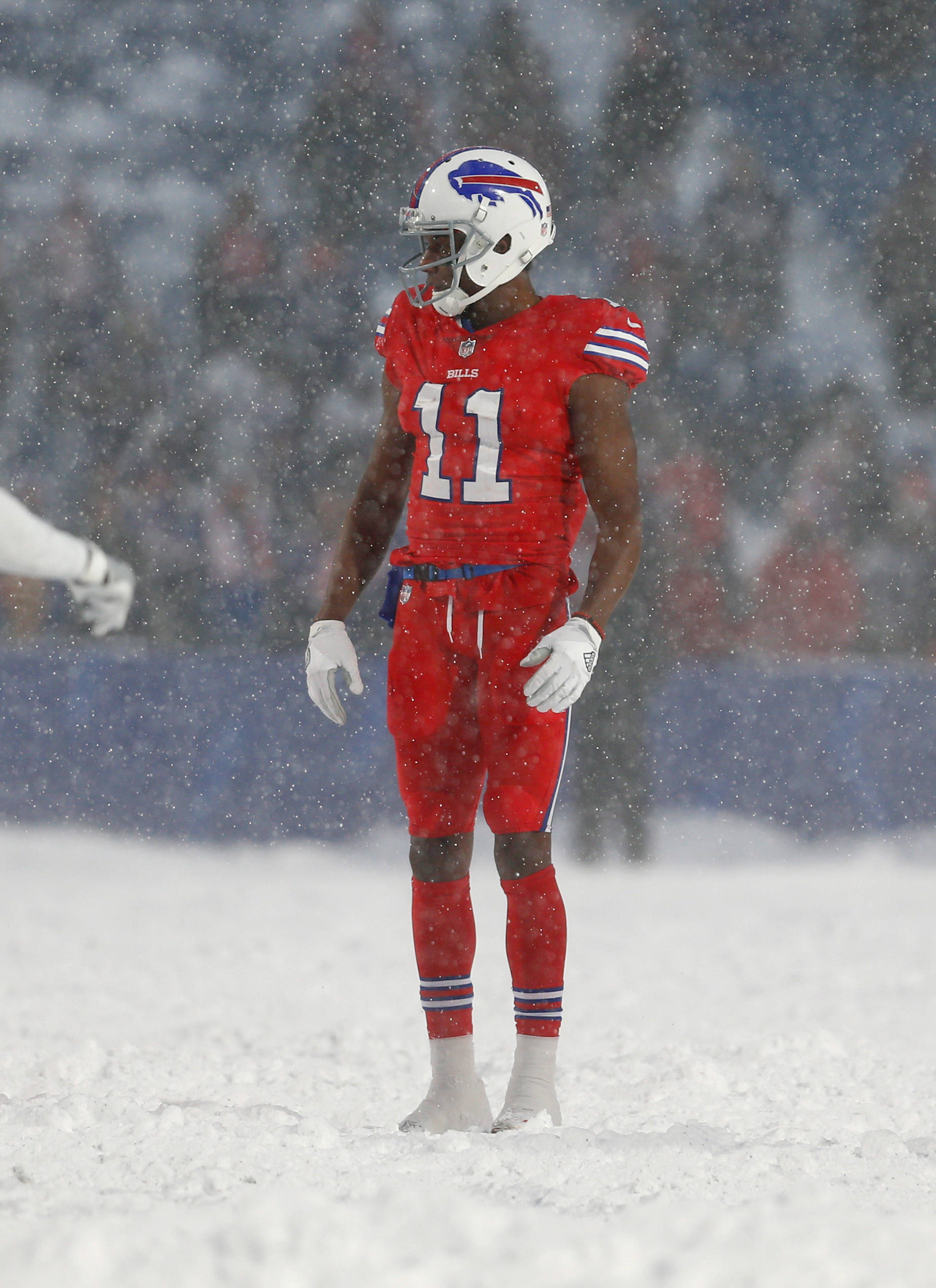Zay Jones 雪中足球場 壁紙 — 一名身穿紅色球衣的布法羅比爾隊美式足球員獨自站在積雪的球場上，雪花在他周圍飄落。
