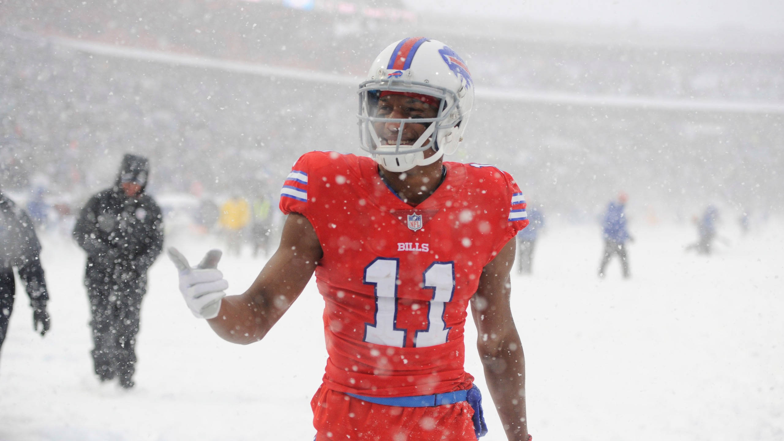 Zay Jones 雪覆球場 壁紙 — 一名水牛城比爾隊的足球員身穿紅色11號球衣，在球場上大雪紛飛時豎起大拇指。