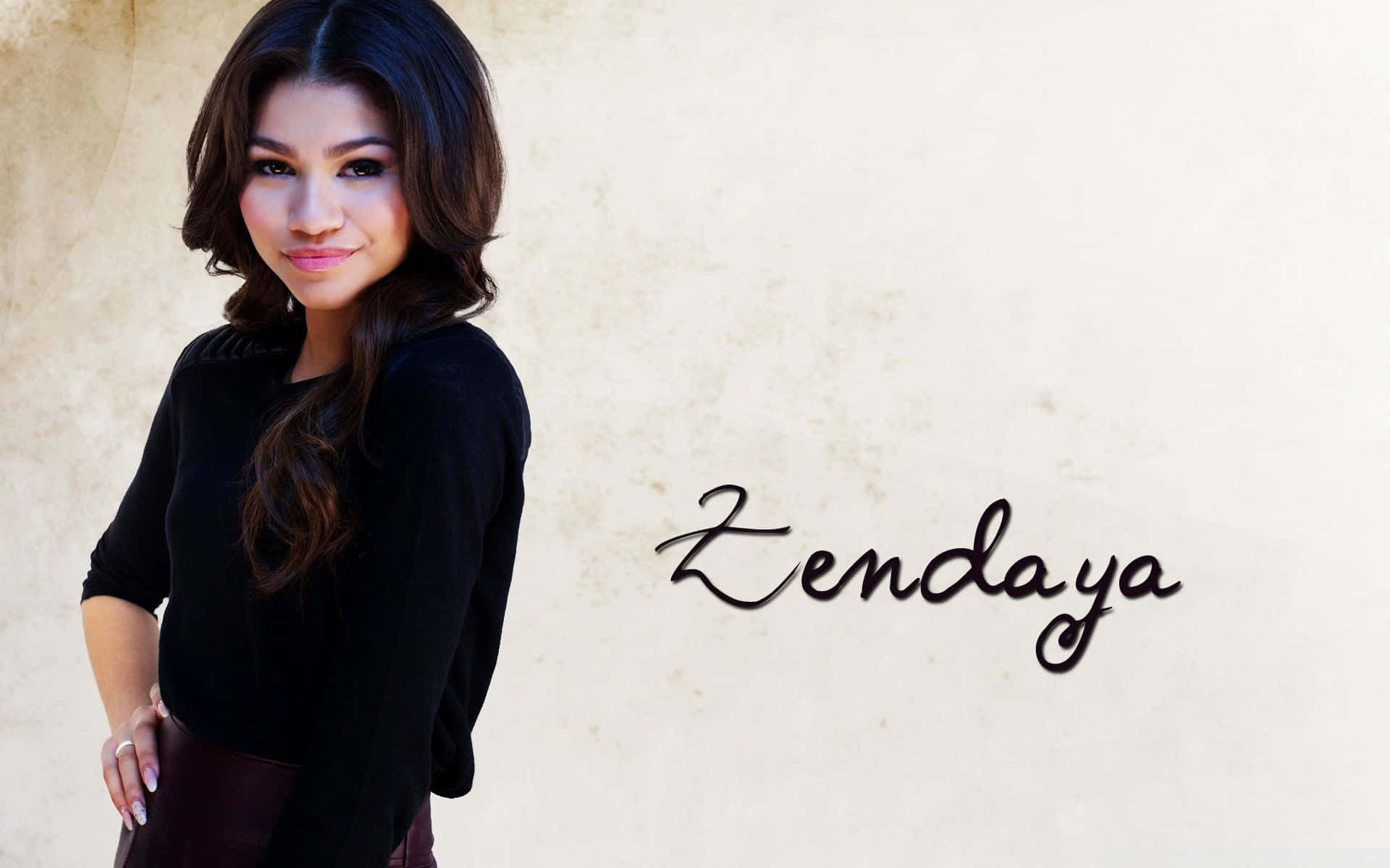 Zendaya 穿著黑色上衣，在名字旁邊微笑。
