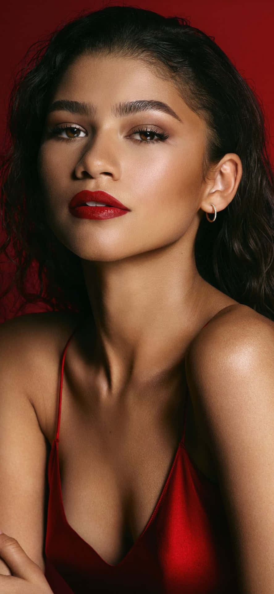 一位穿著紅色連衣裙、塗著紅色口紅的女性看著相機。