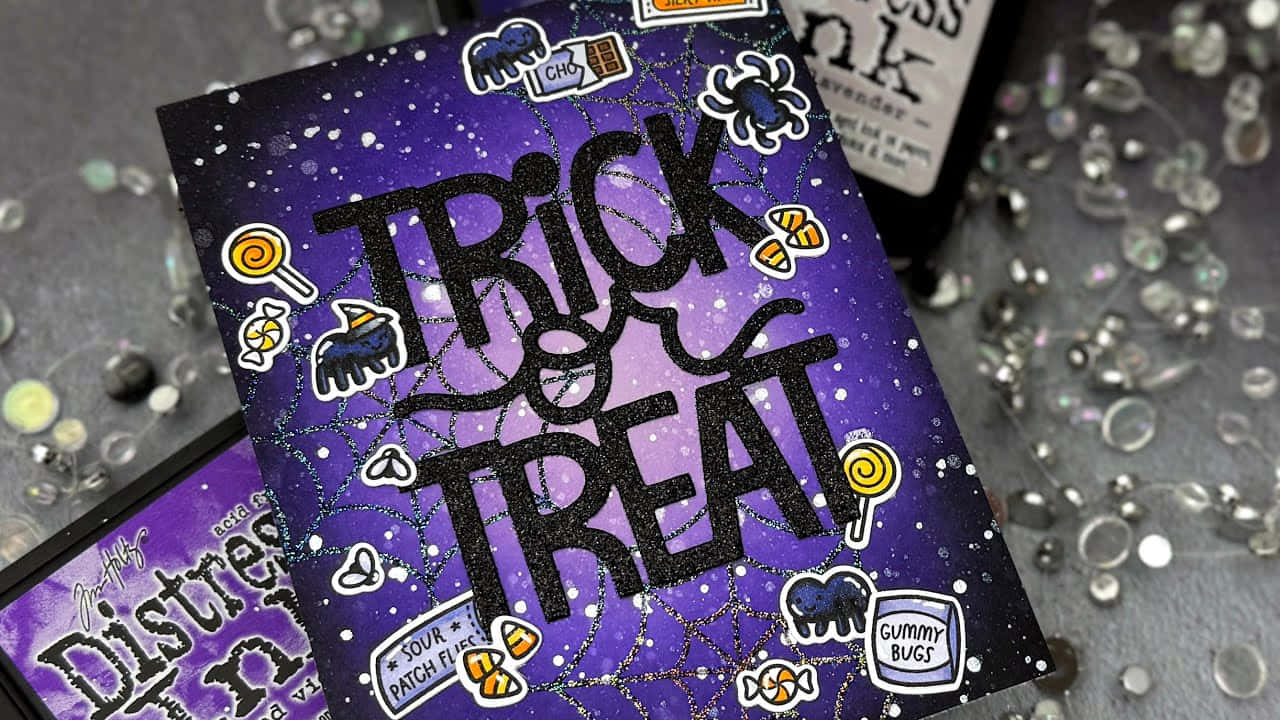  壁紙 — 一張閃亮紫色萬聖節卡，以粗體黑色字寫著「Trick or Treat」，周圍環繞糖果貼紙和蜘蛛網細節。