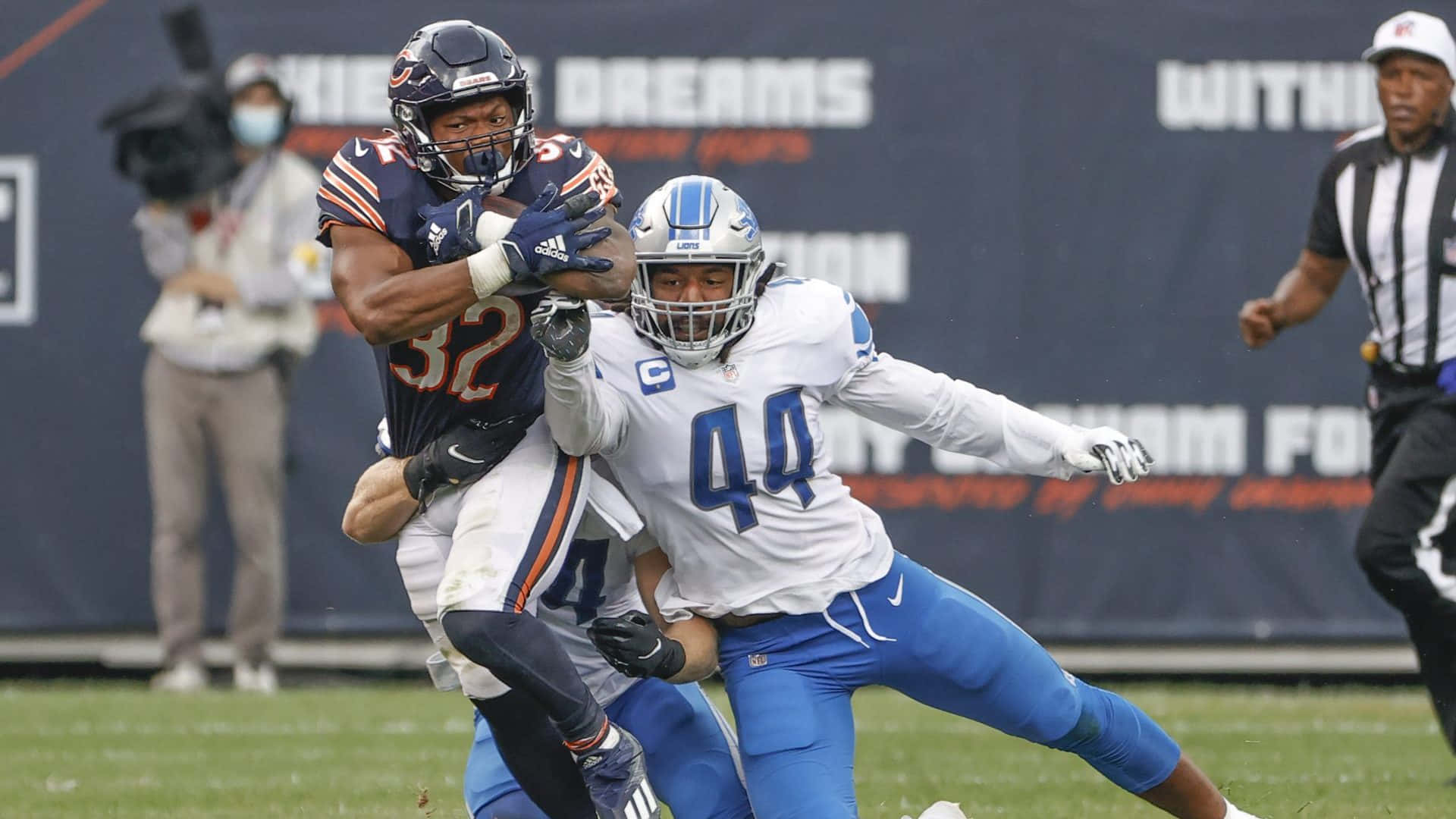  壁紙 — 芝加哥熊隊的跑衛在綠色球場上進行的一場激烈的NFL比賽中被底特律獅隊的線衛擒抱。
