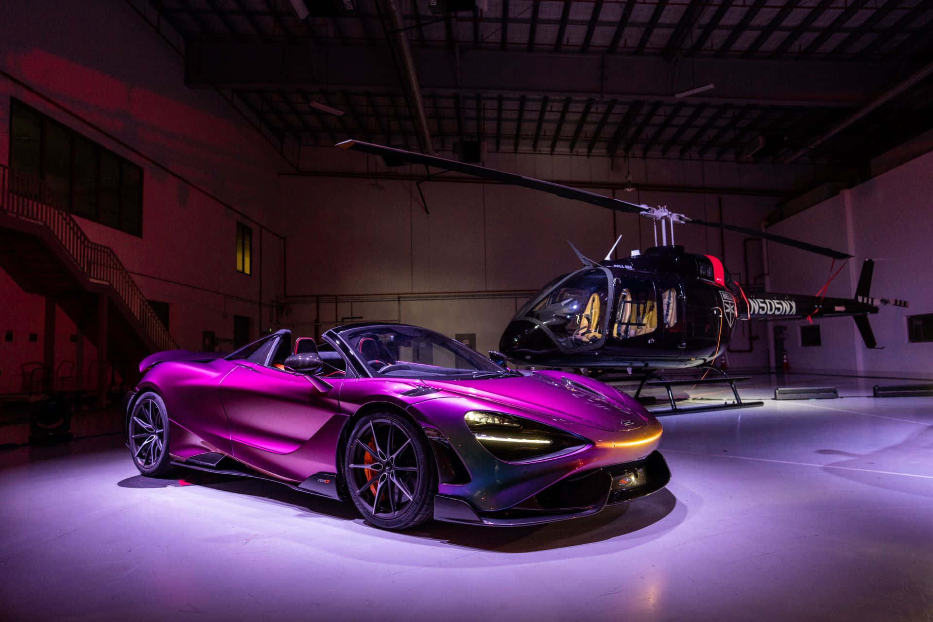 Mclaren 765lt 桌布 壁紙 — 一輛充滿活力的紫色McLaren跑車在昏暗的機庫中，在聚光燈下與一架黑色直升機並排閃耀。