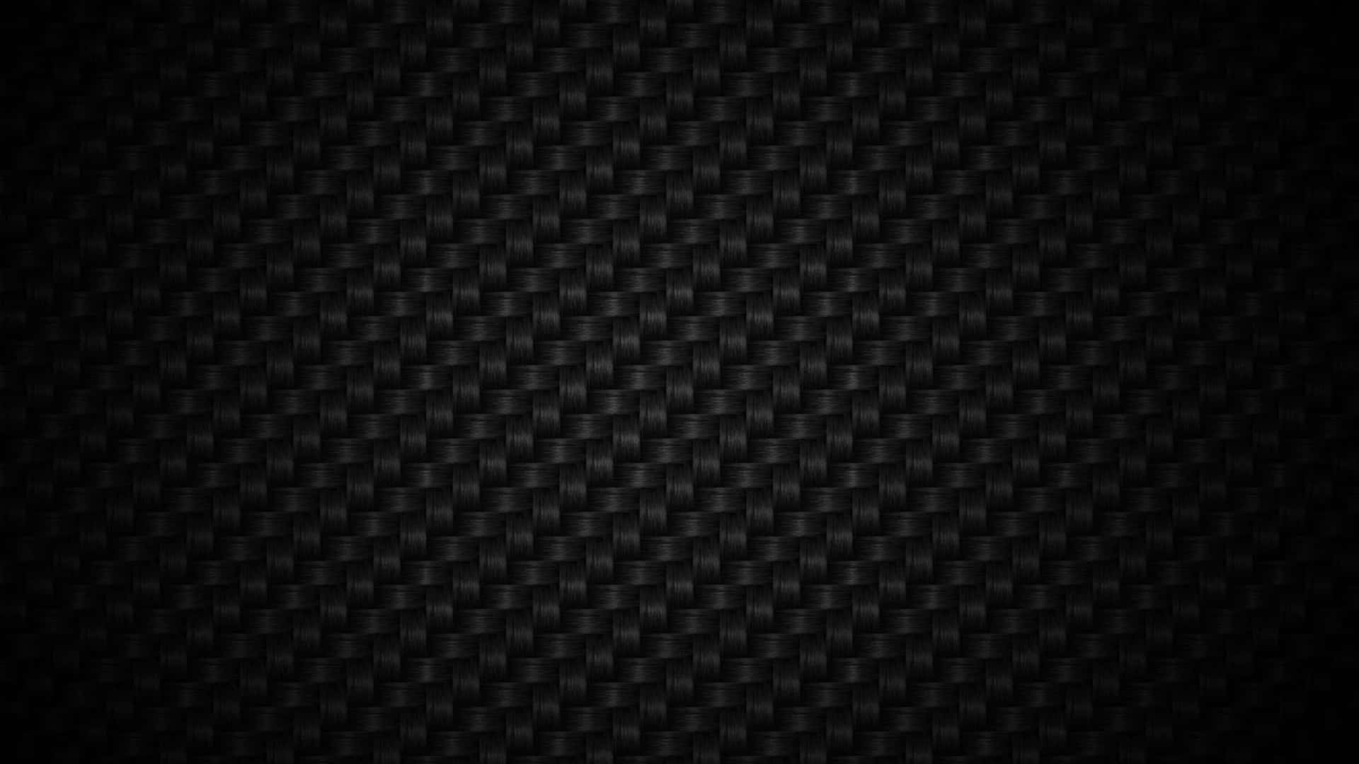 暗房中電腦螢幕的 Zoom 背景 壁紙 — 黑色碳纖維質感的特寫，帶有細膩的編織圖案和漸變燈光。
