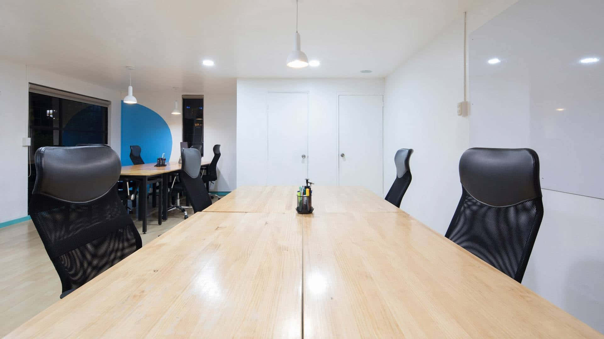 您的辦公室煥然一新：Zoom Office 壁紙 — 一個現代化的會議室，長木桌周圍擺放著黑色人體工學椅，上方有明亮的吊燈。