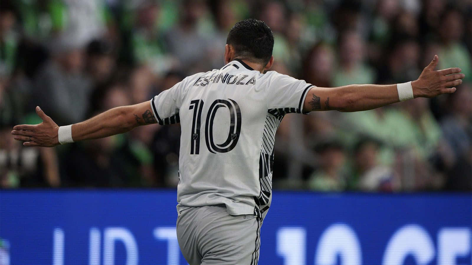 壁紙 — 足球員查維亞·靴南迪斯（Chicharito）在球場人群中張開雙臂慶祝，身穿10號球衣。