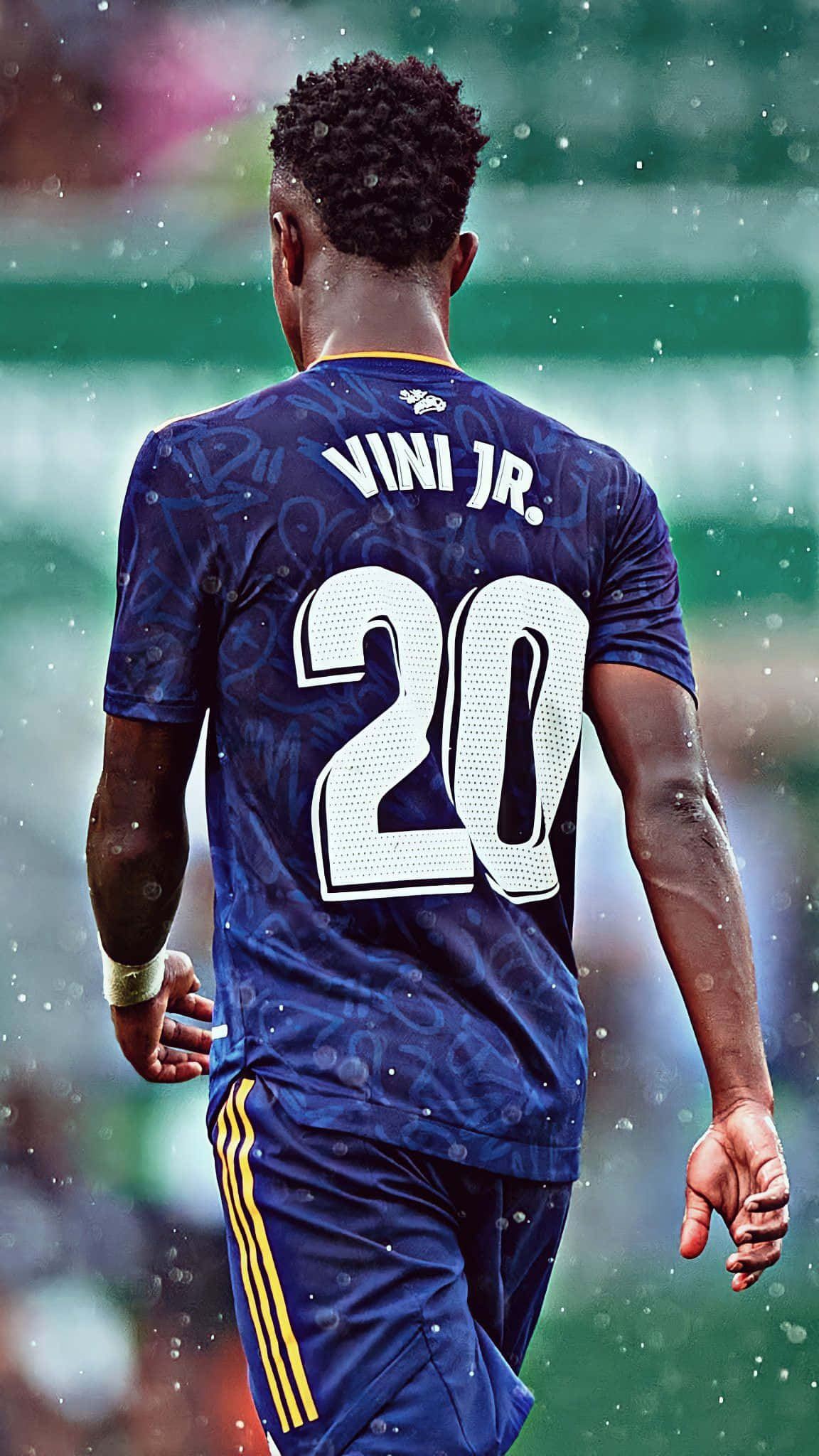 Vini Jr 4K 桌布 壁紙 — 一名身穿藍色球衣、背號20、名字Vini Jr的足球運動員在雨中的球場上走開，背景是模糊的球場燈光。