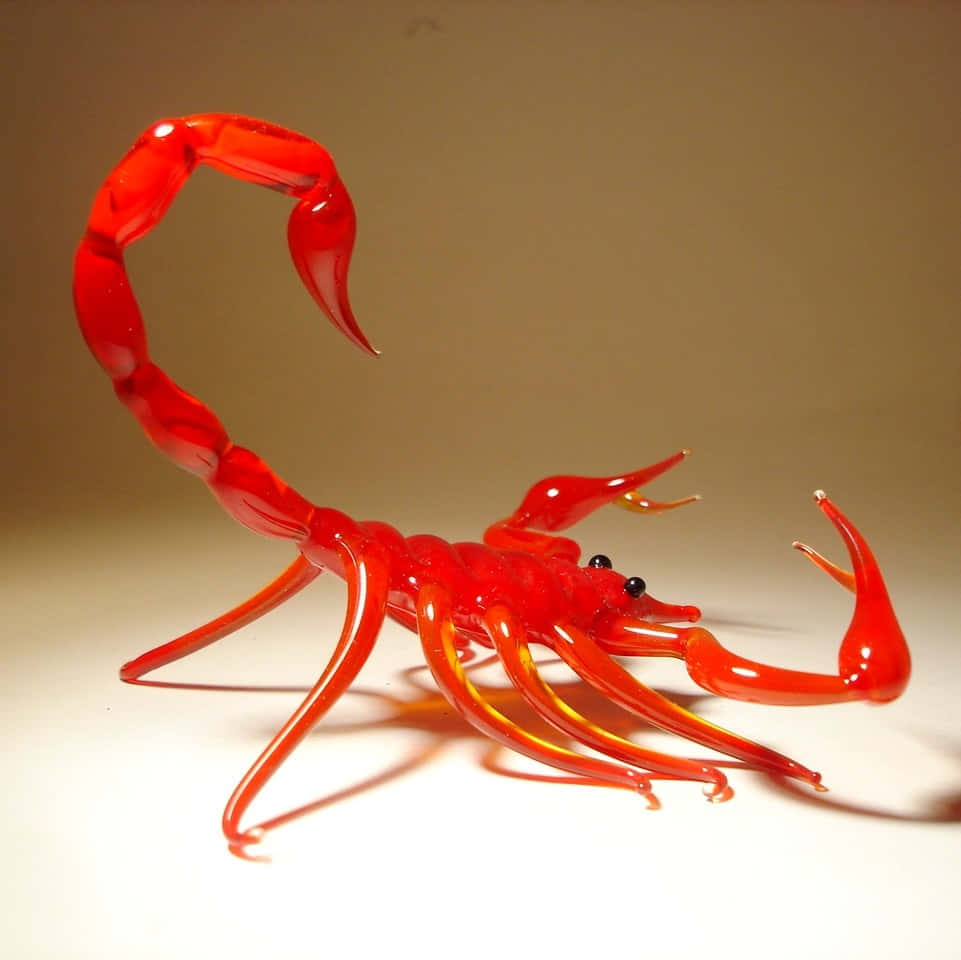 Red Scorpion 桌布 壁紙 — 一件充滿活力的紅色玻璃蠍子雕塑，表面光滑，帶有琥珀色亮點，立於中性米色背景前。