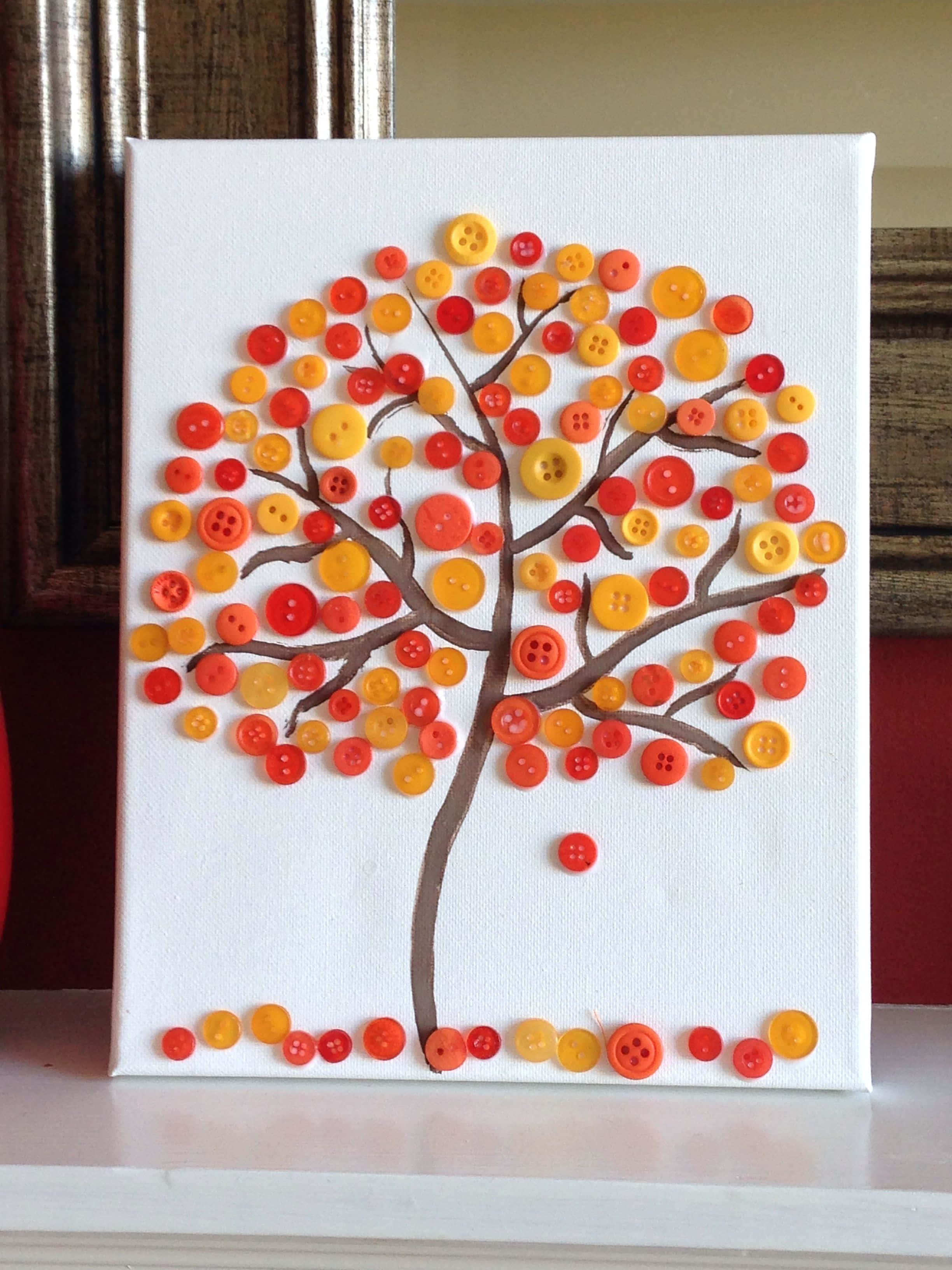 Fall Crafts 桌布 壁紙 — 一件手工製作的樹木藝術品，由紅色、橙色和黃色鈕扣在白色畫布上製成，放在架子上。
