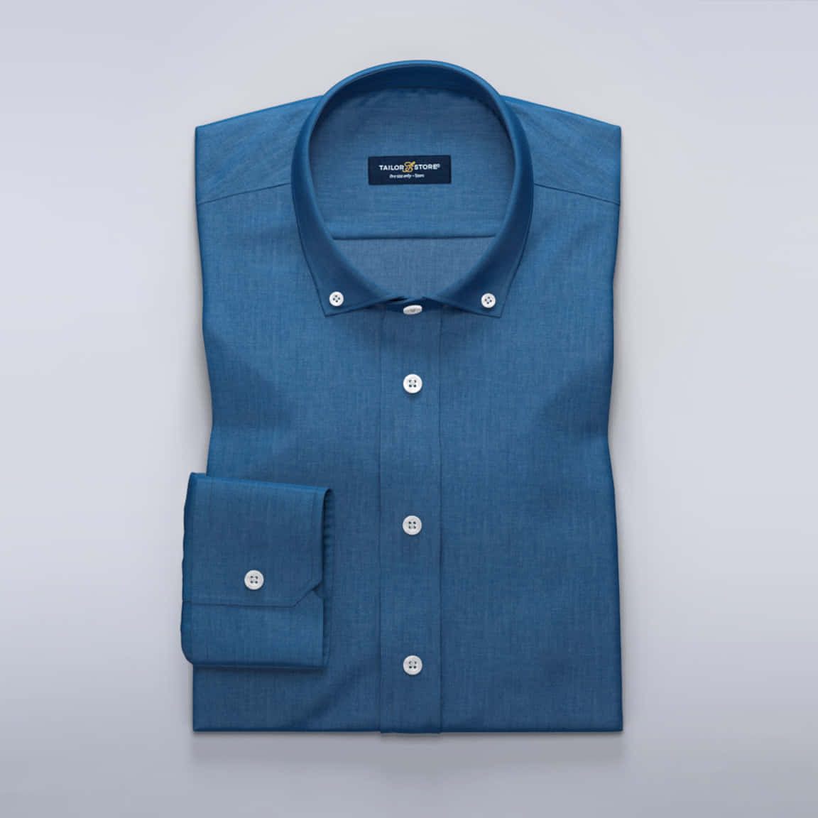 Denim Blue 桌布 壁紙 — 一件整齊折疊的藍色鈕扣襯衫，帶有白色鈕扣，展示在純淺灰色背景上。