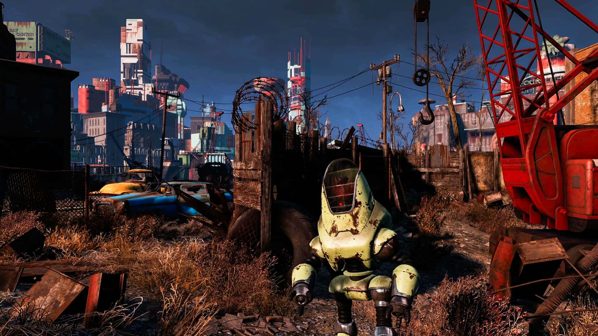Fallout 4 Wasteland 桌布 壁紙 — 一件生鏽的動力裝甲套裝坐在一個破敗的城市荒地中，周圍有破爛的汽車和衰敗的城市天際線，天空陰暗。