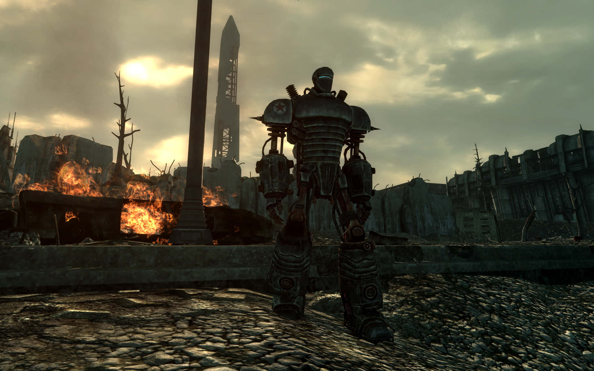 Liberty Prime 桌布 壁紙 — 一件重型裝甲的動力裝甲服站在廢墟城市景觀中，背景有火焰在陰沉天空下燃燒。