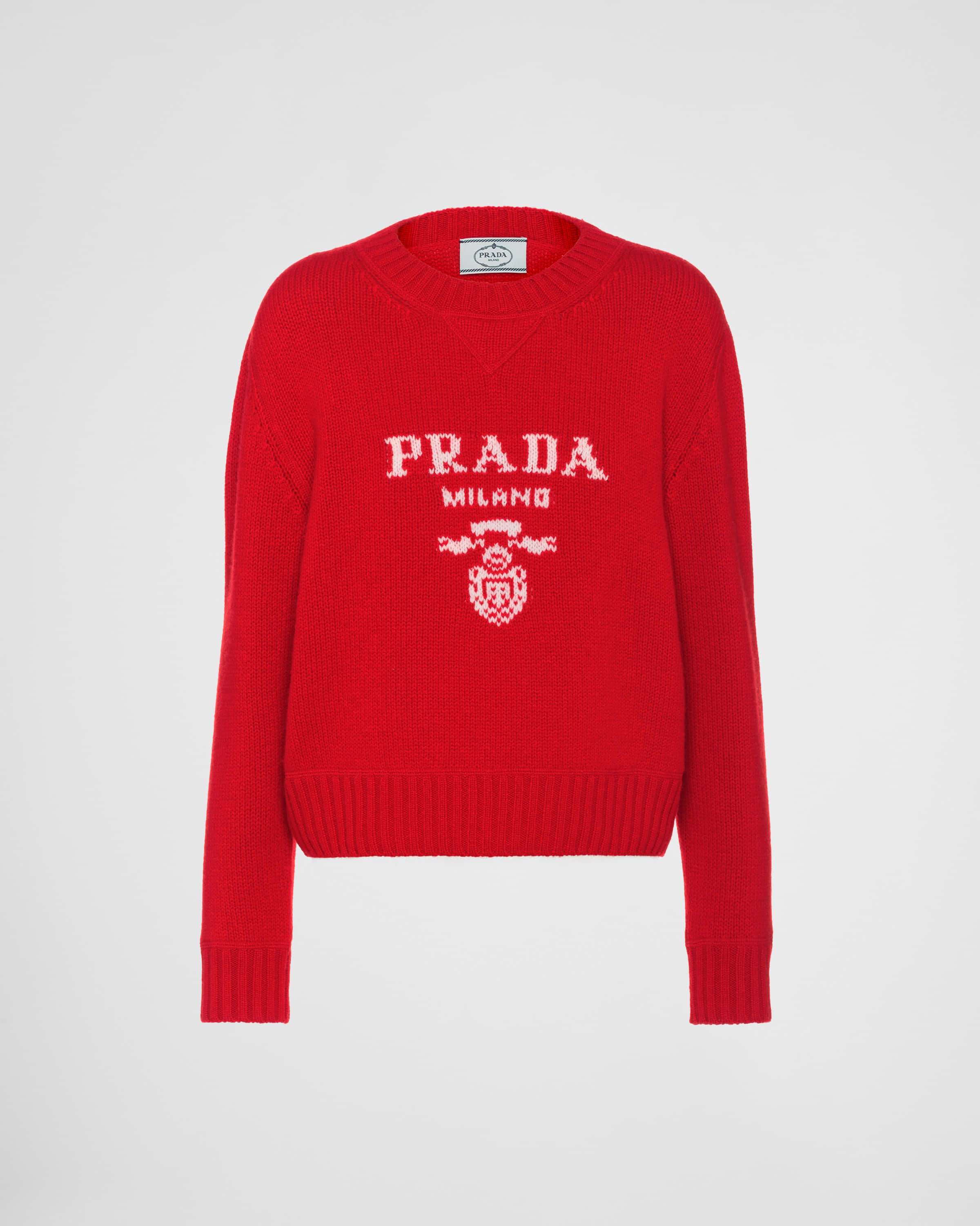 Red Sweater 桌布 壁紙 — 一件鮮紅色Prada毛衣，帶有白色針織標誌和徽章，展示在純白色背景上。