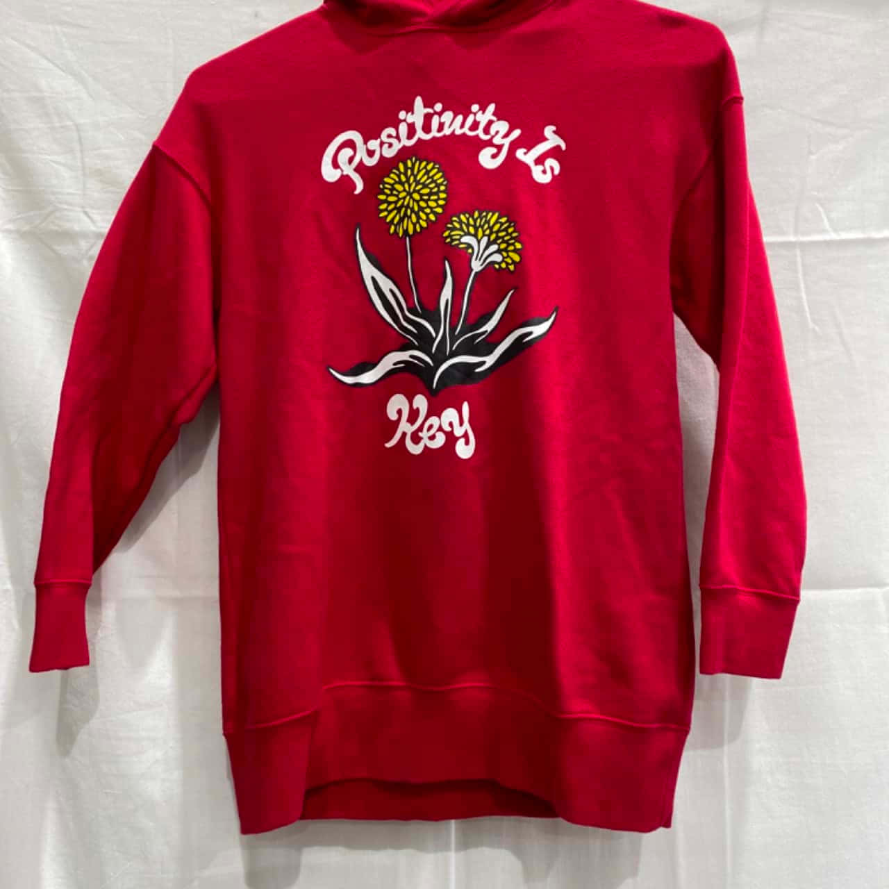 Red Hoodie 桌布 壁紙 — 一件鮮紅色連帽衛衣，白色背景上印有蒲公英的白色圖案和「Positivity Is Key」字句。