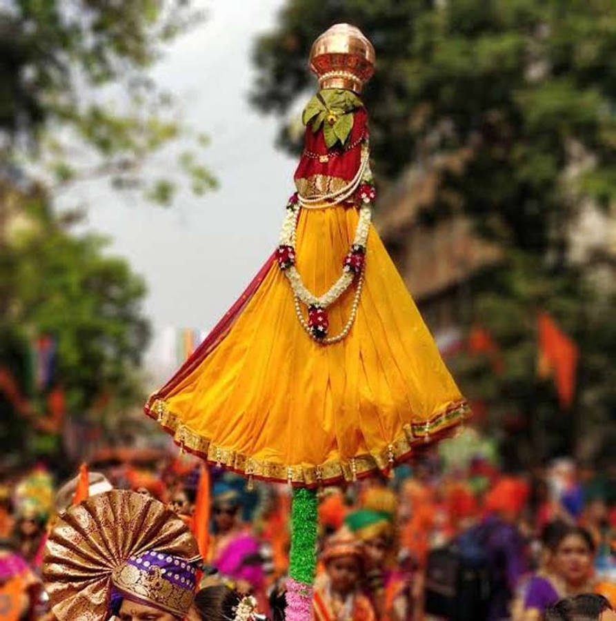 Gudi Padwa 桌布 壁紙 — 一件鮮黃色、飾有珠子和花朵的傳統服飾，在色彩繽紛的街頭節日期間被扛在綠色桿子上。
