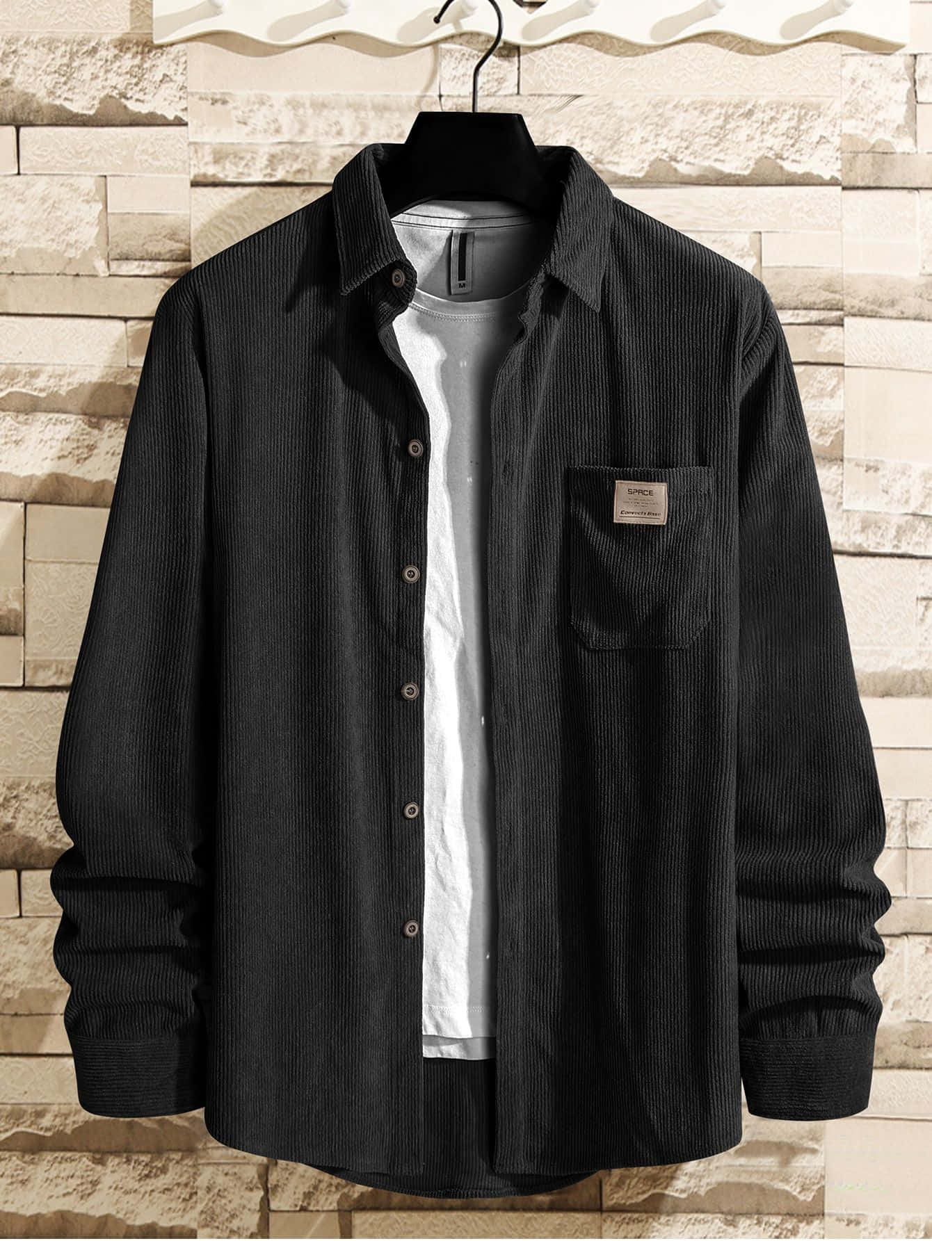Black Clothing 桌布 壁紙 — 一件黑色燈芯絨恤衫，前面有鈕扣和胸袋，掛在衣架上，背景是紋理石牆。