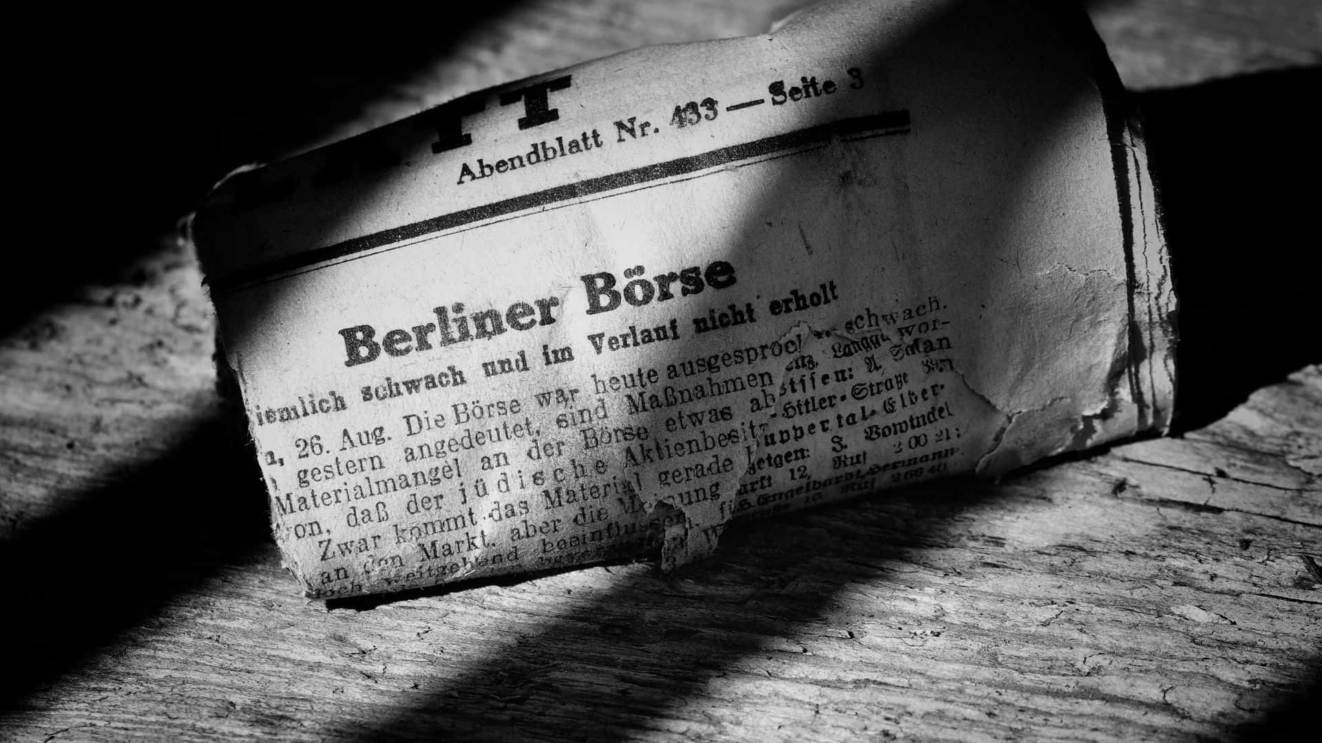 Black And White Newspaper 桌布 壁紙 — 一份標題為 Berliner Börse 的風化德國報紙放在粗糙的木板上，其老舊的頁面在戲劇性的燈光下顯示出裂縫和褪色的文字。