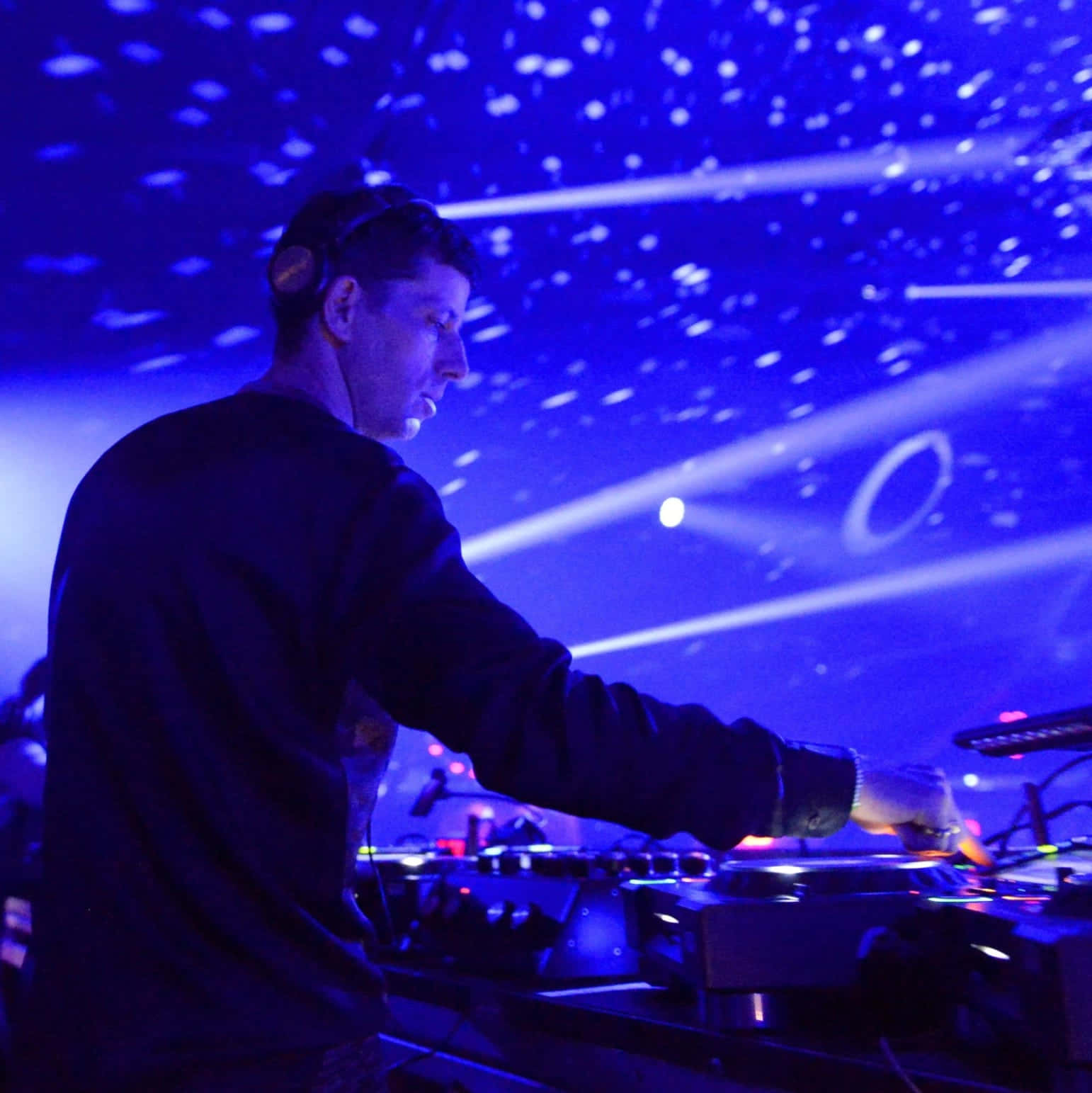 DJ 桌布 壁紙 — 一位DJ在夜店的星空藍色燈光表演下側面混音。